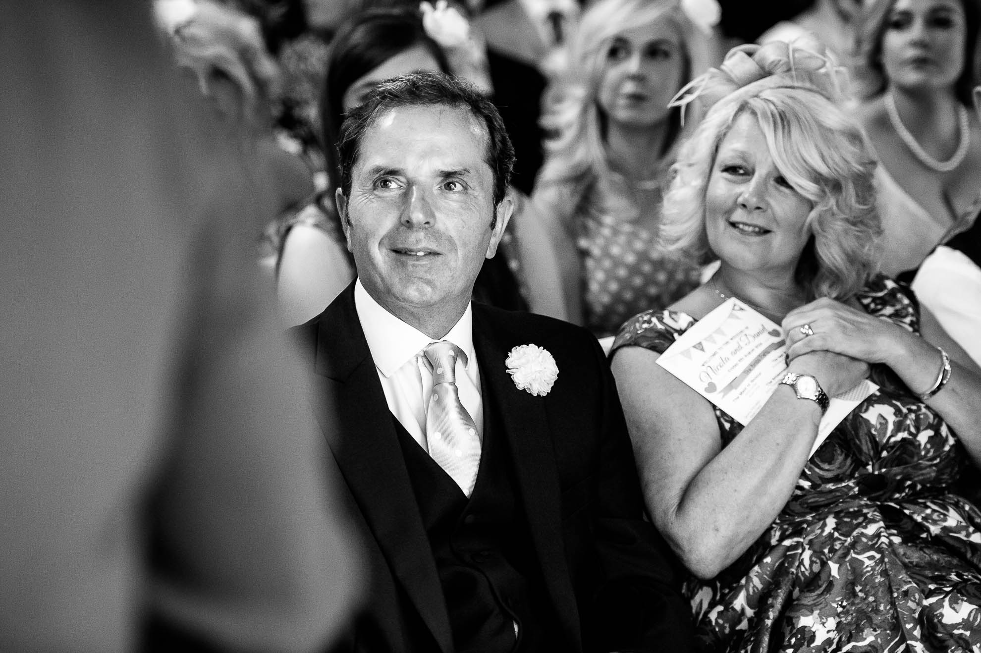Father of the bride smiles as the newlyweds exchange rings