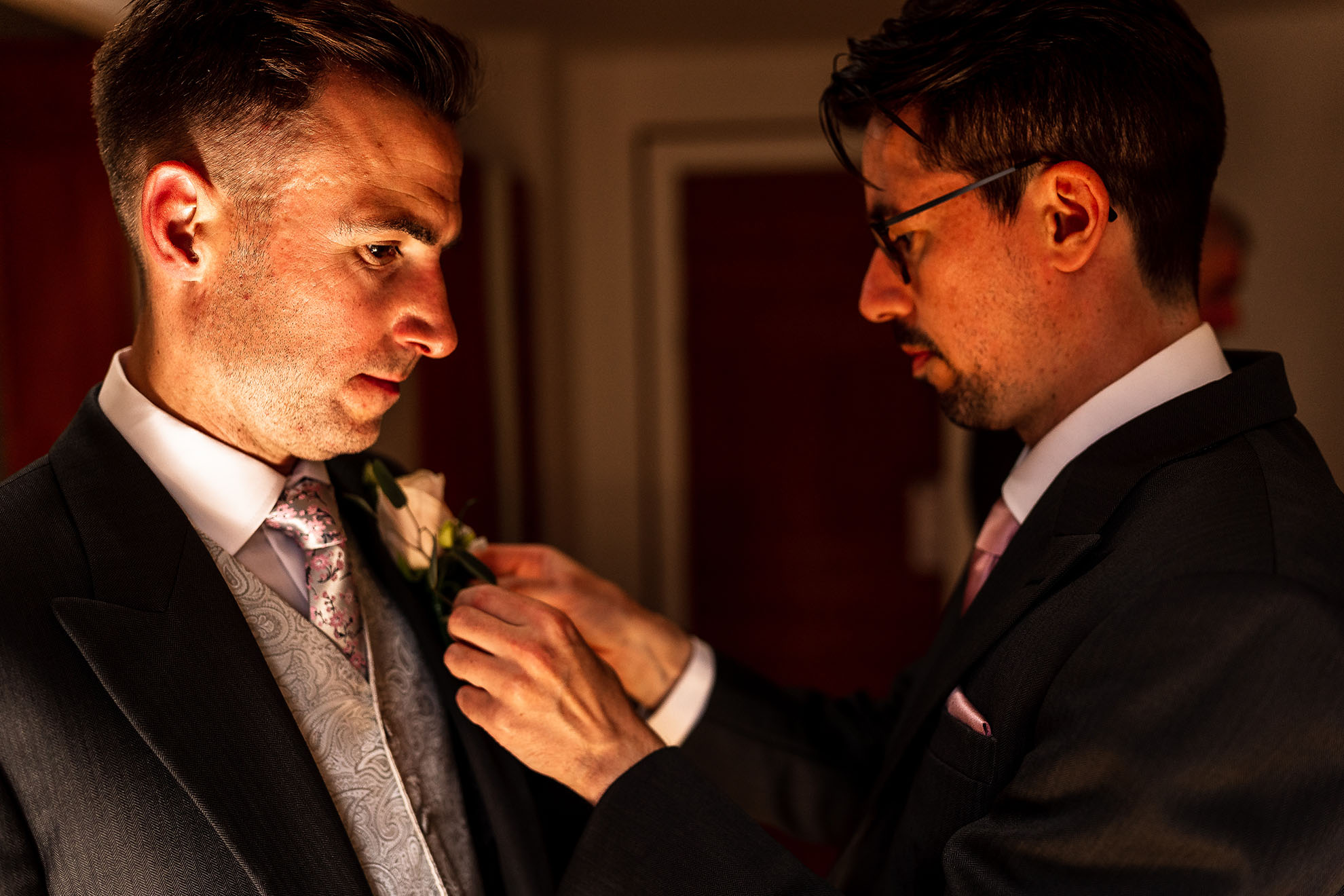best man adjusts groom's lapel flower