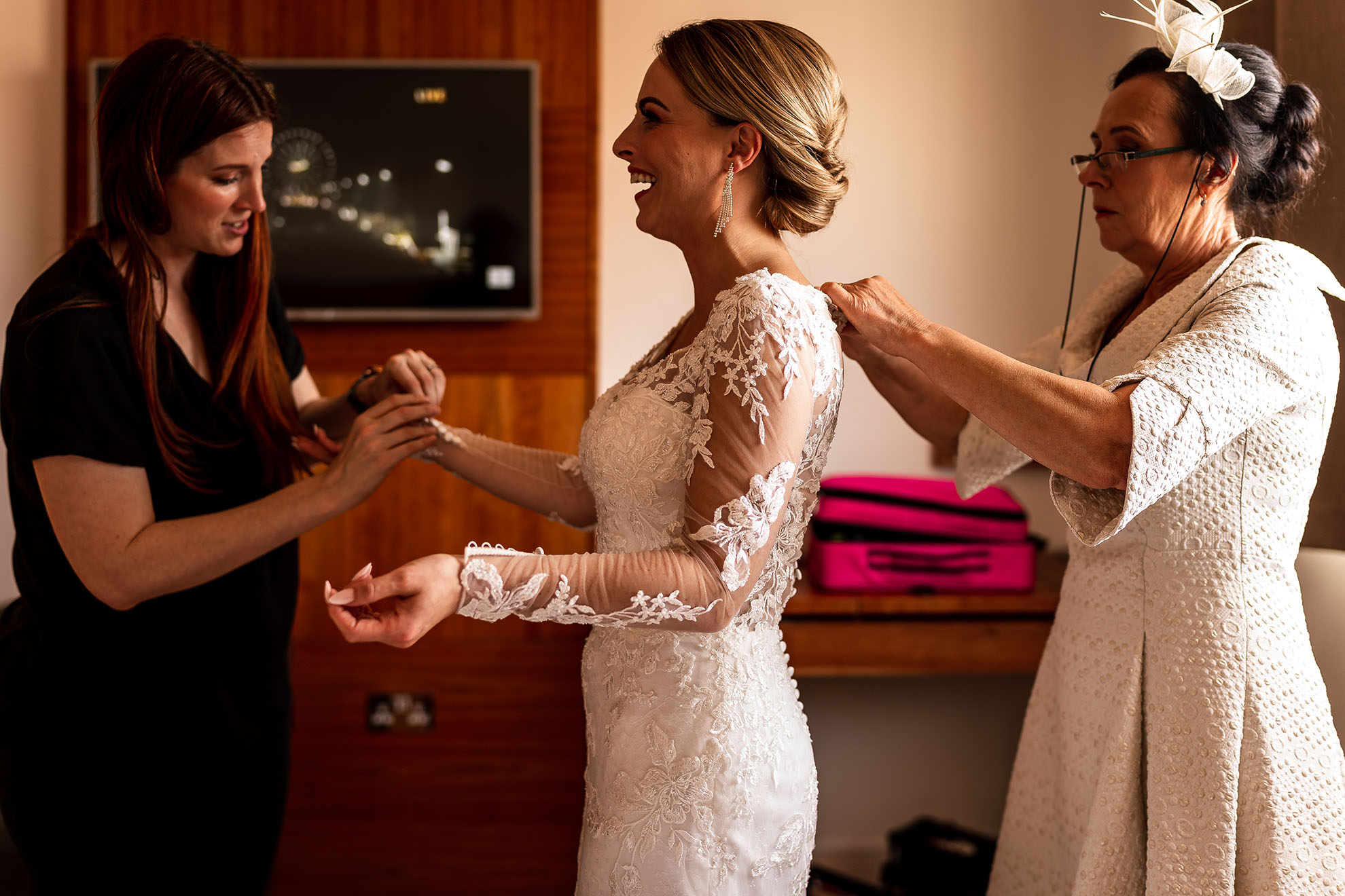 mother of the bride helps bride into her wedding dress