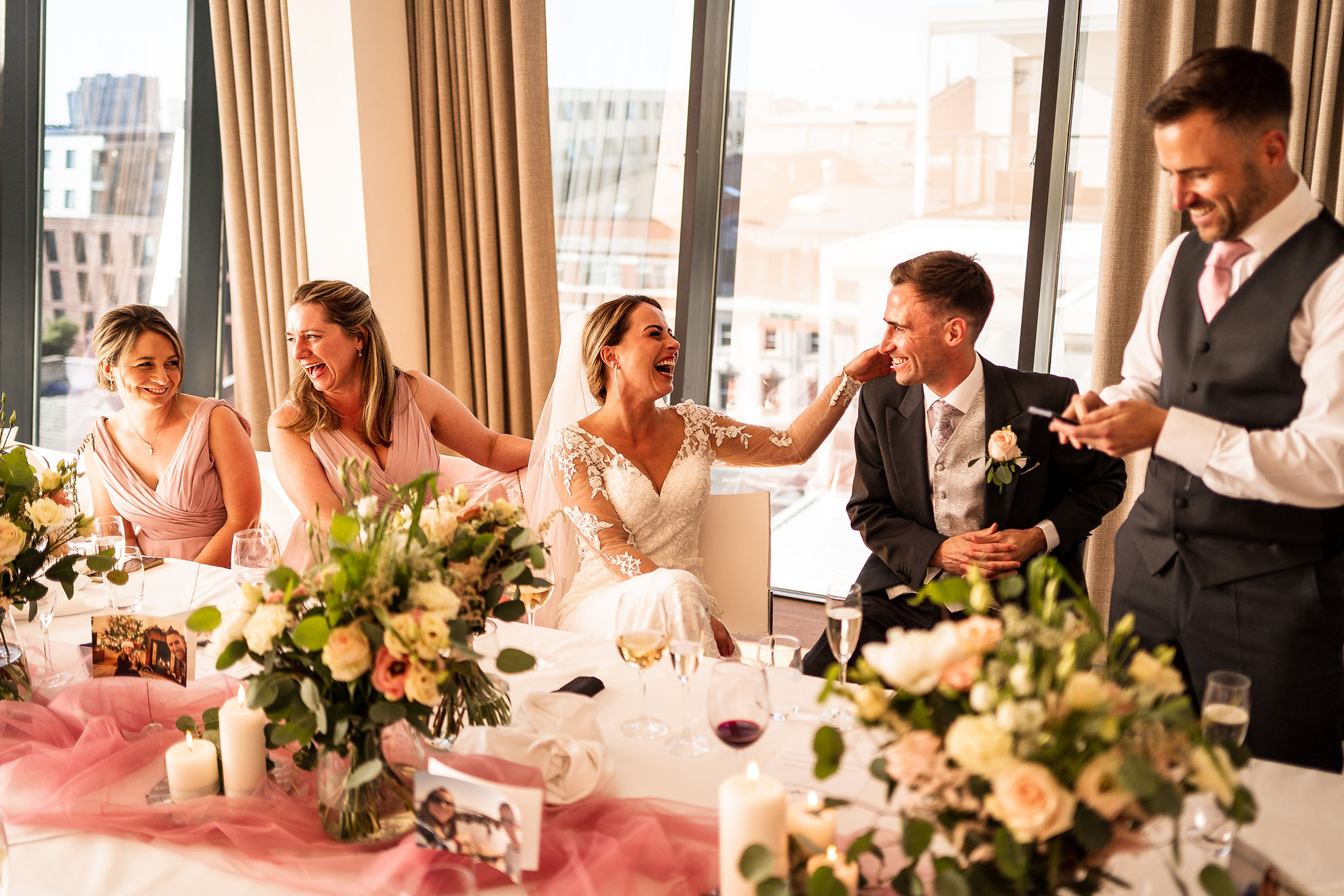 Bride and groom luagh during best man's speech