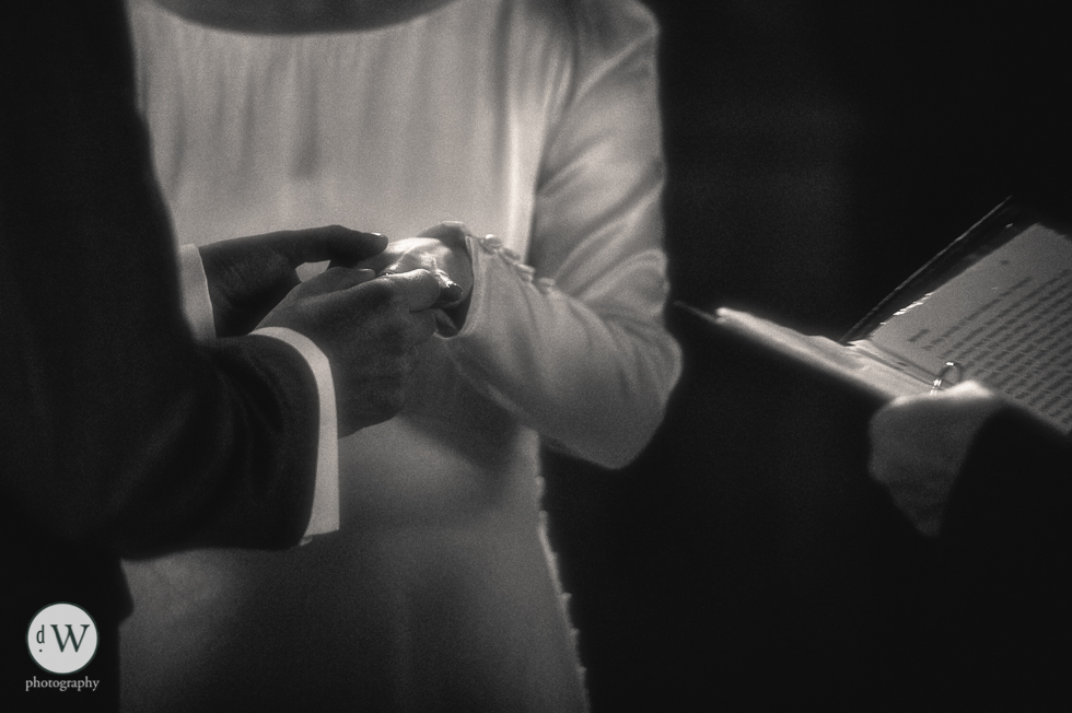 Groom places wedding ring on brides hand close up
