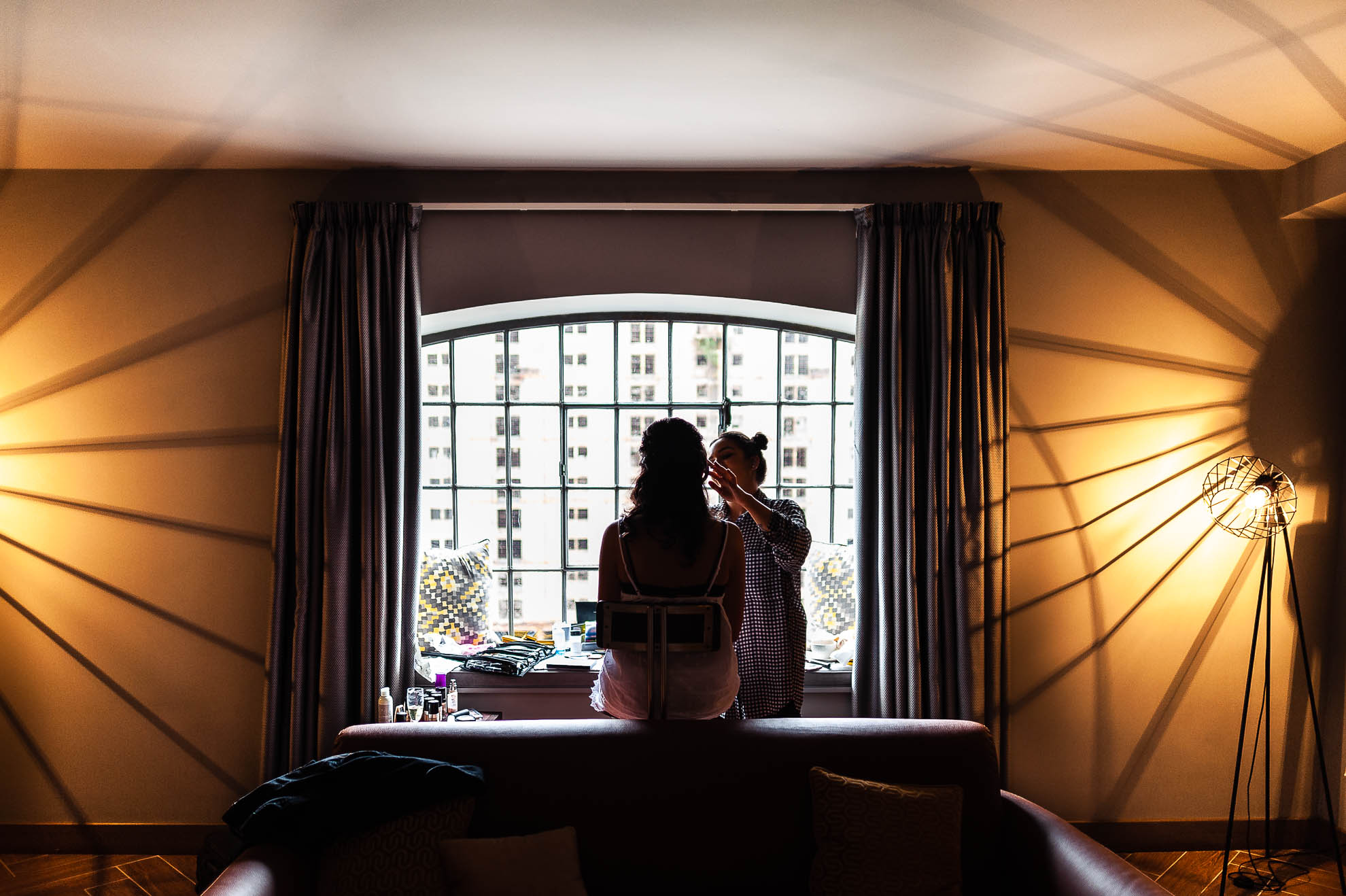 Bride having make up applied in window 