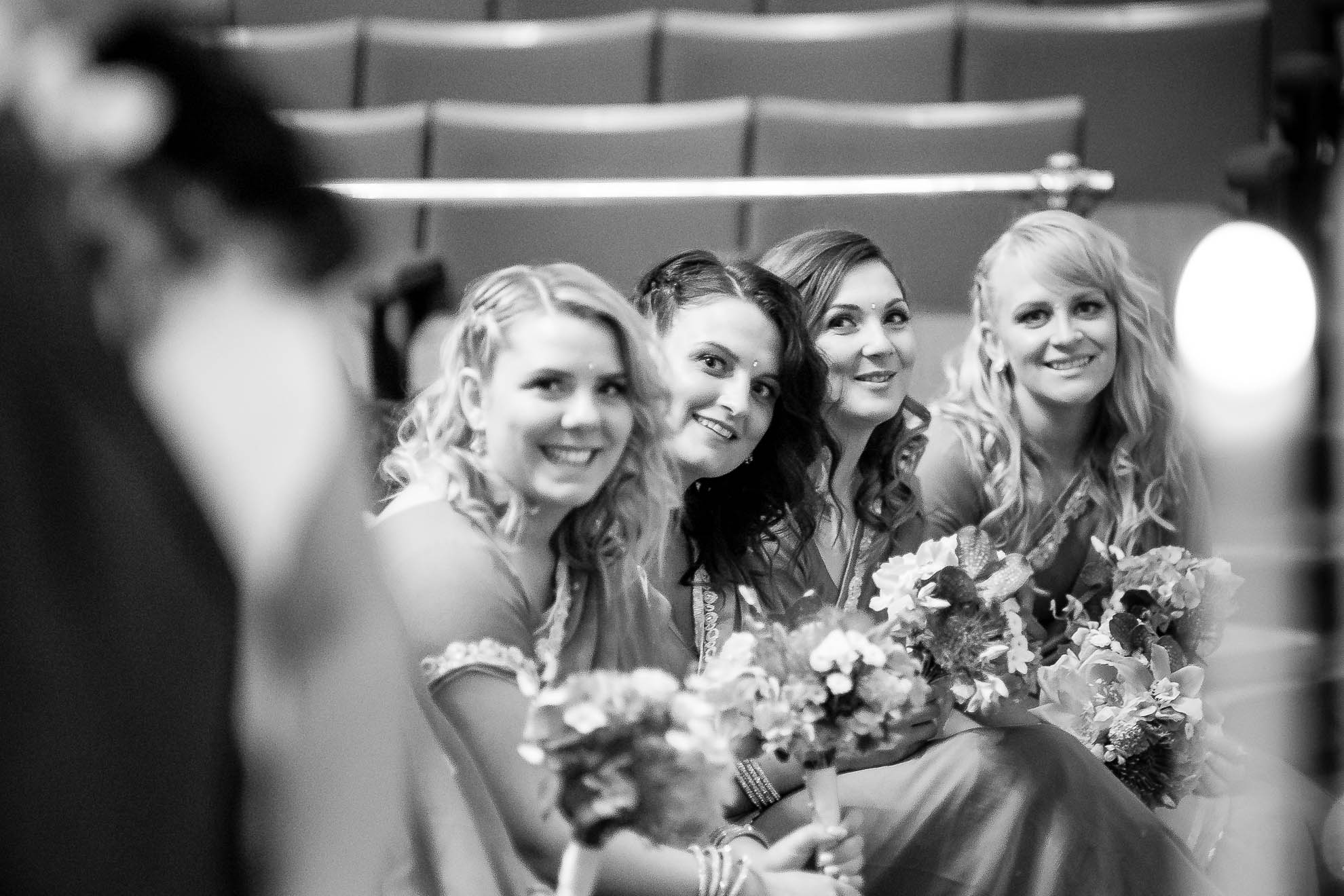 bridesmaids smile as they look at the bride and groom