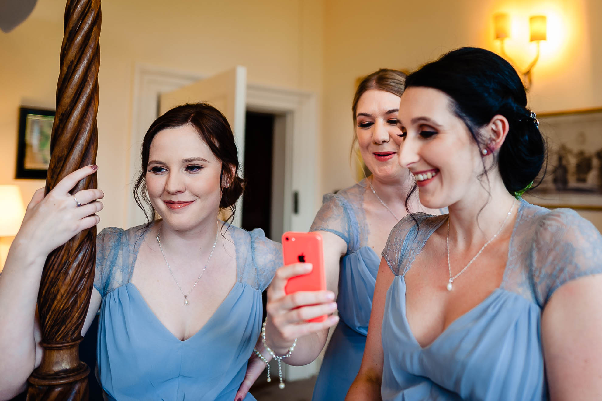 bridesmaids smile and take photograph of bride