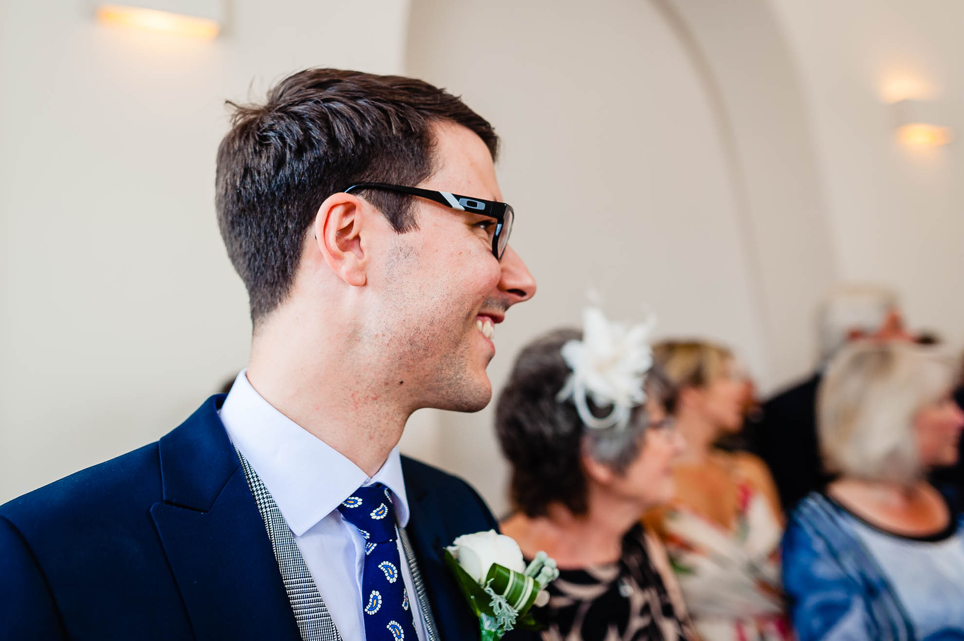 Groom smiles at his bride as she walks up the ailse