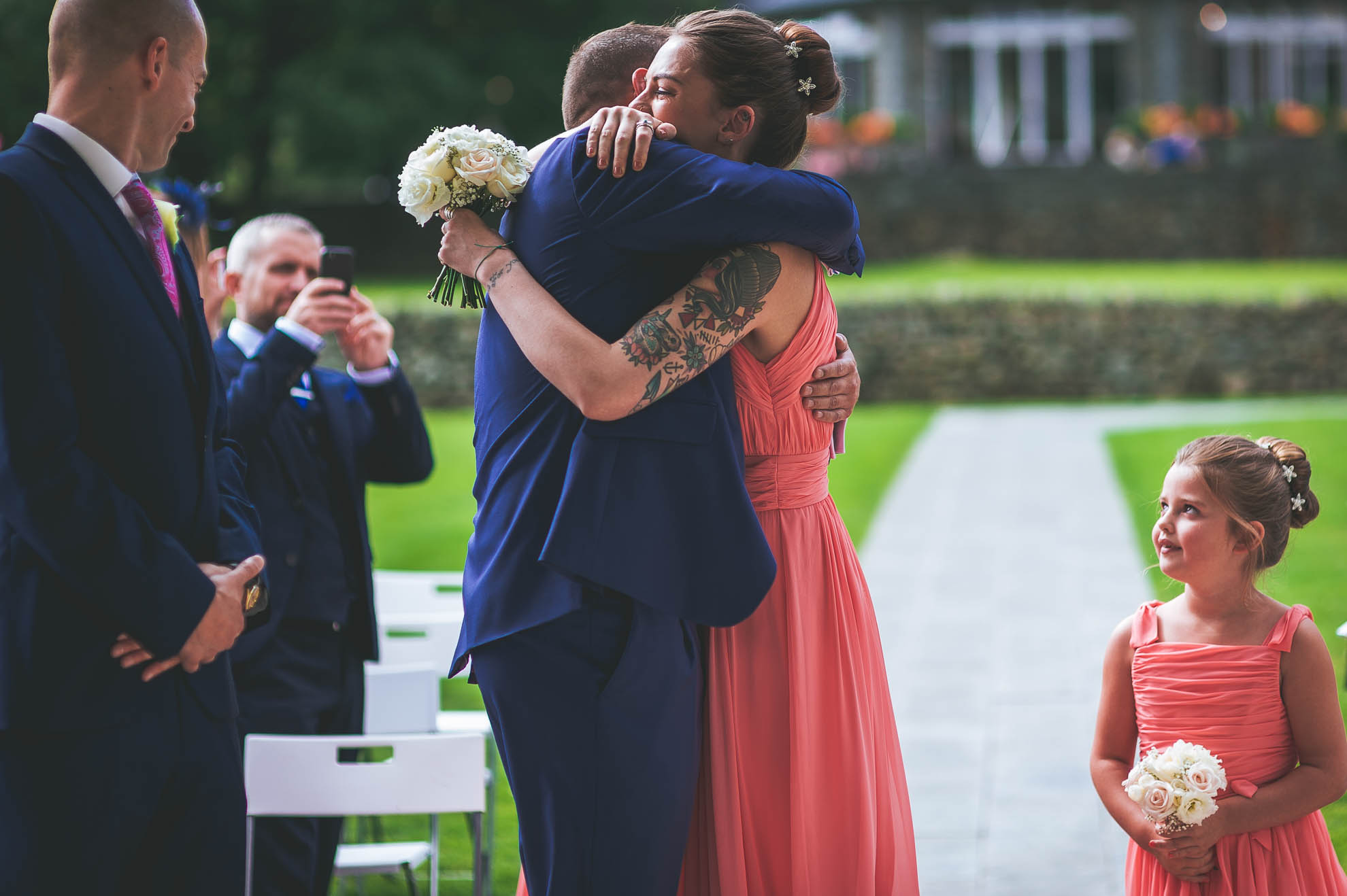 Bridesmaid hugs groom