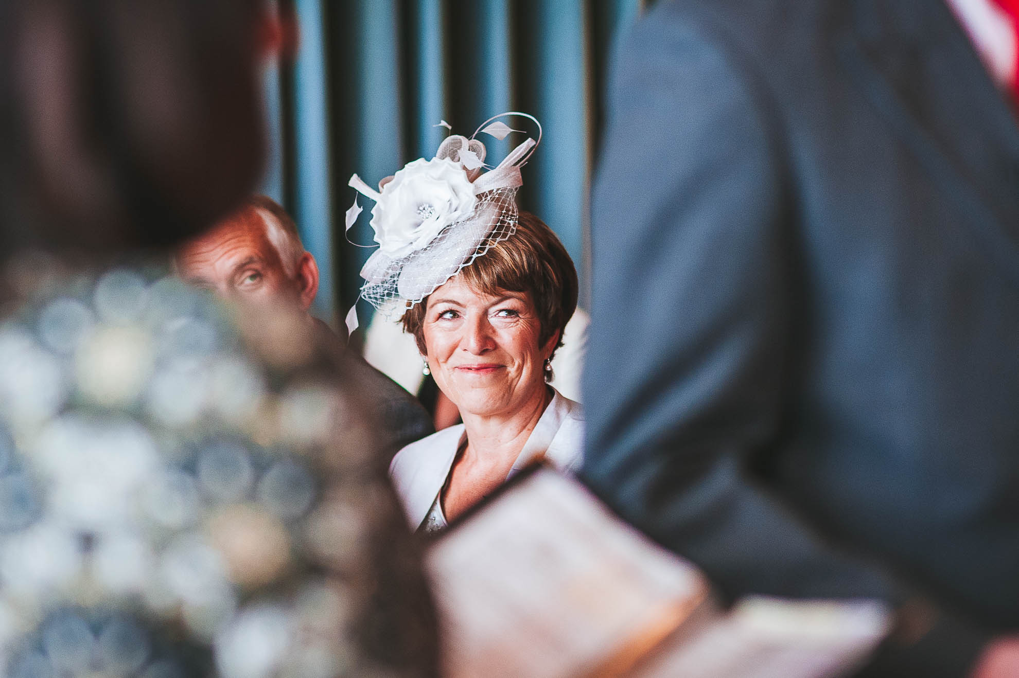 A proud mother of the bride looks on during the exchange of rings