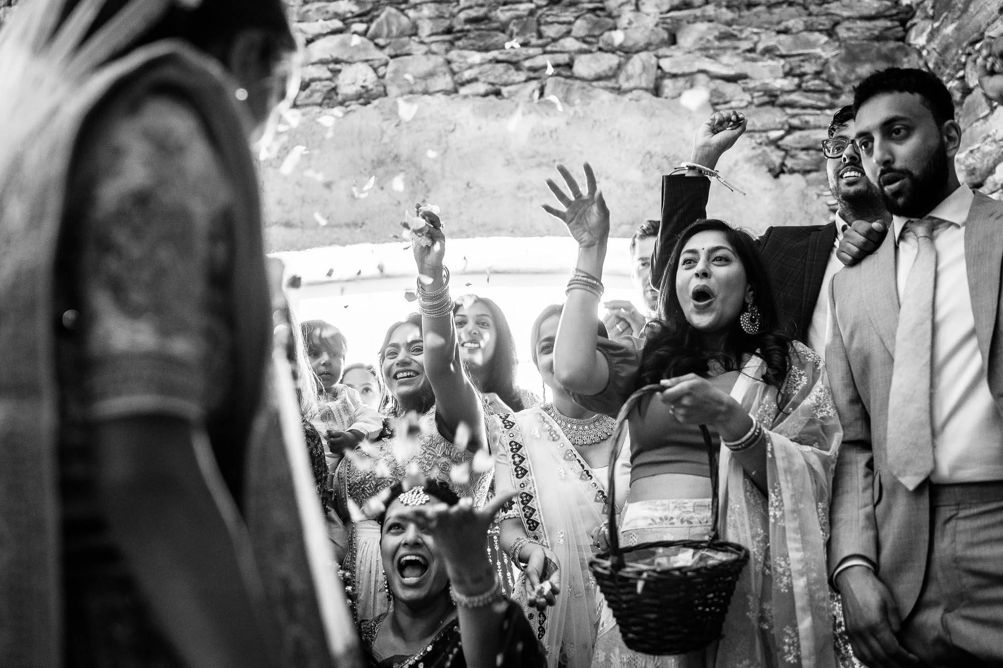 Wedding guests shower the bride and groom with flower petals during the ceremony