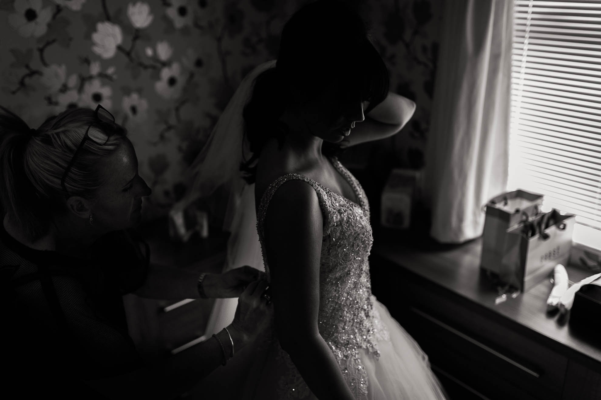 the bridesmaid adjusts the brides wedding dress