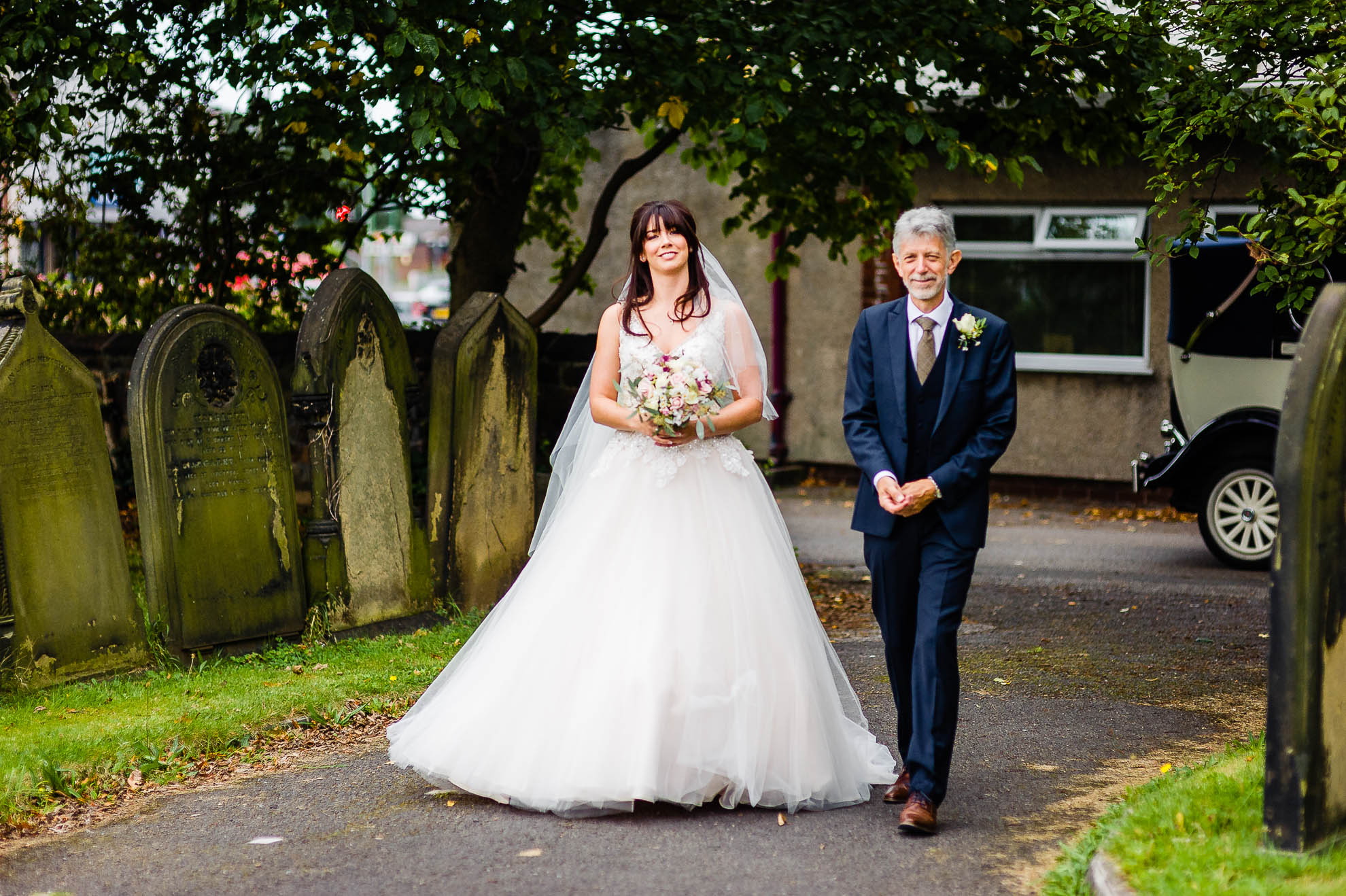 the bride and her father walk to the church