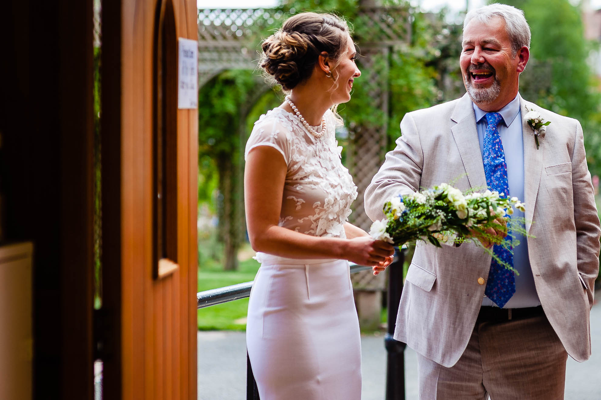 Bride shares a joke with the father of the bride outside the church