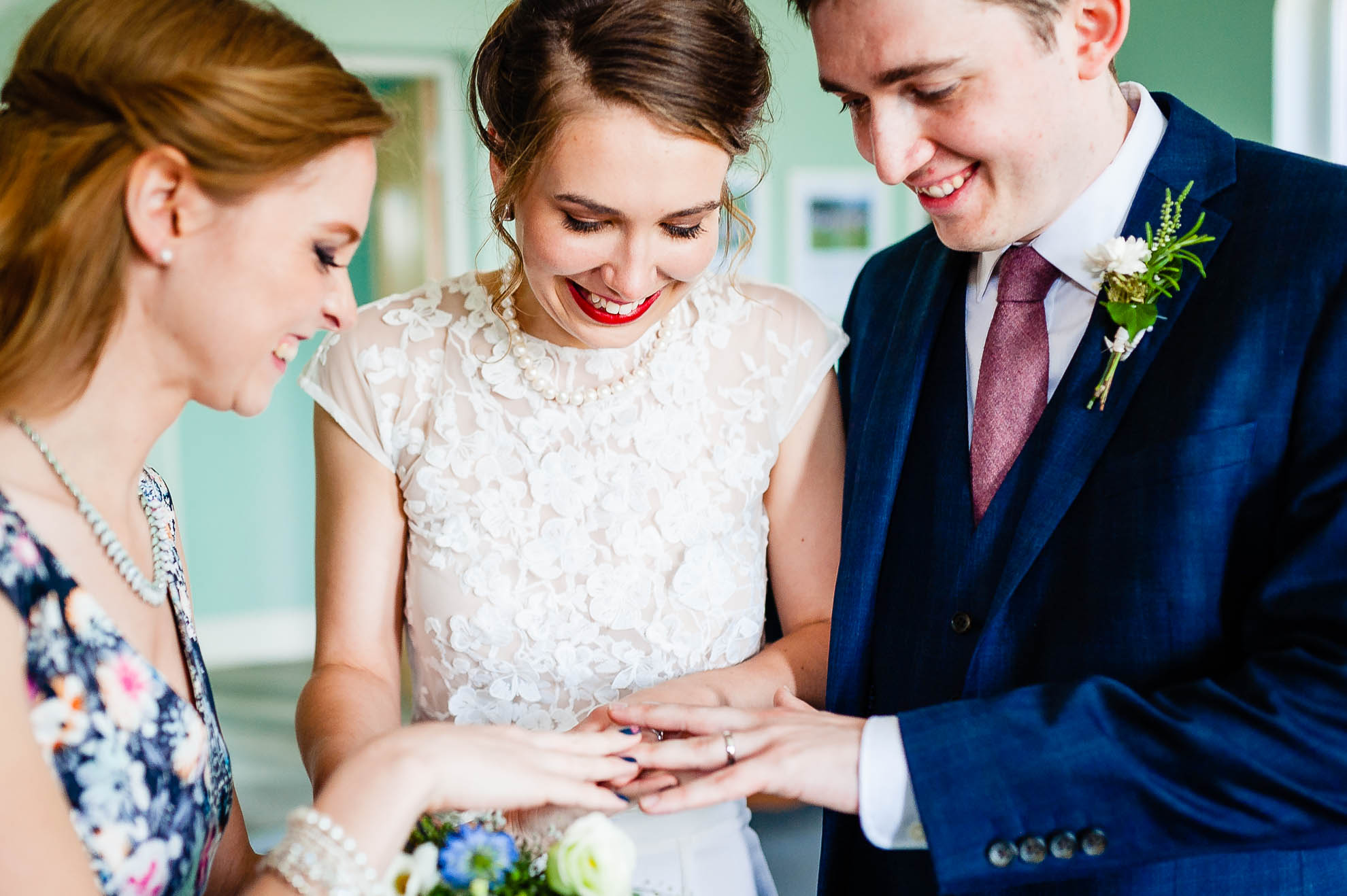 Bride and groom show wedding rings to witness