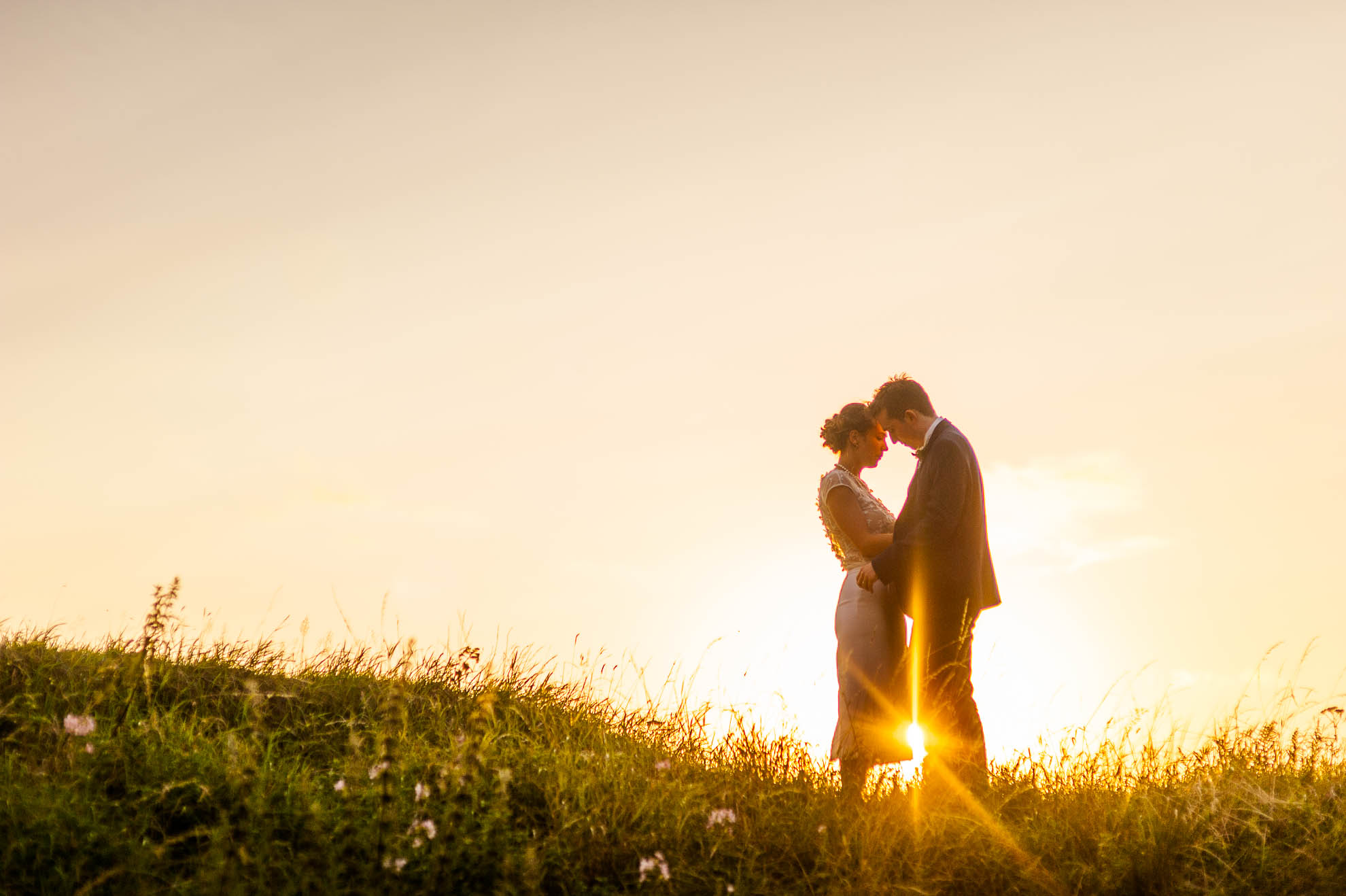 Bride and groom hold each other in the sunset