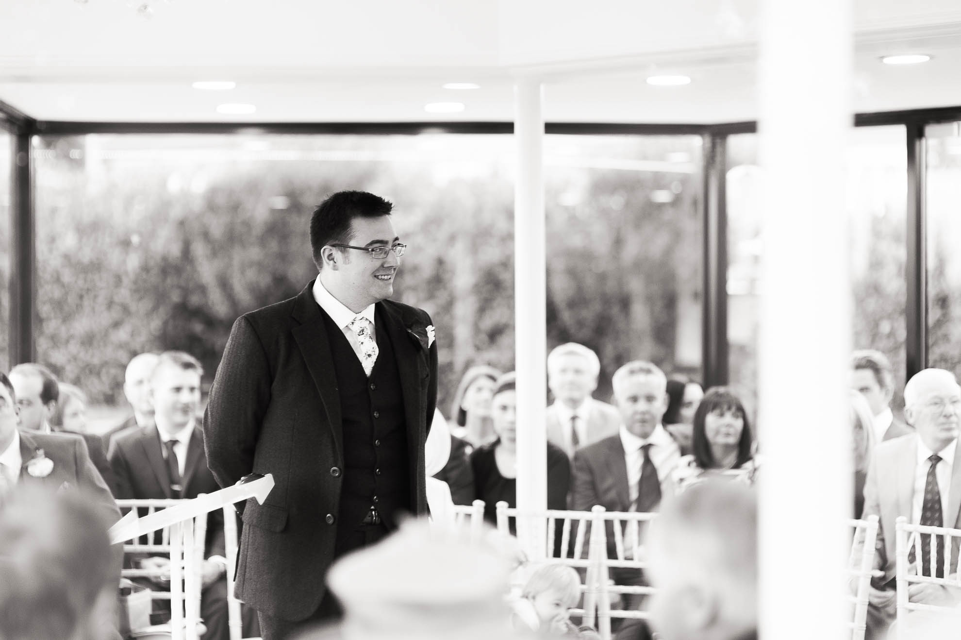 Groom smiles as he waits for the bride in the pavillion