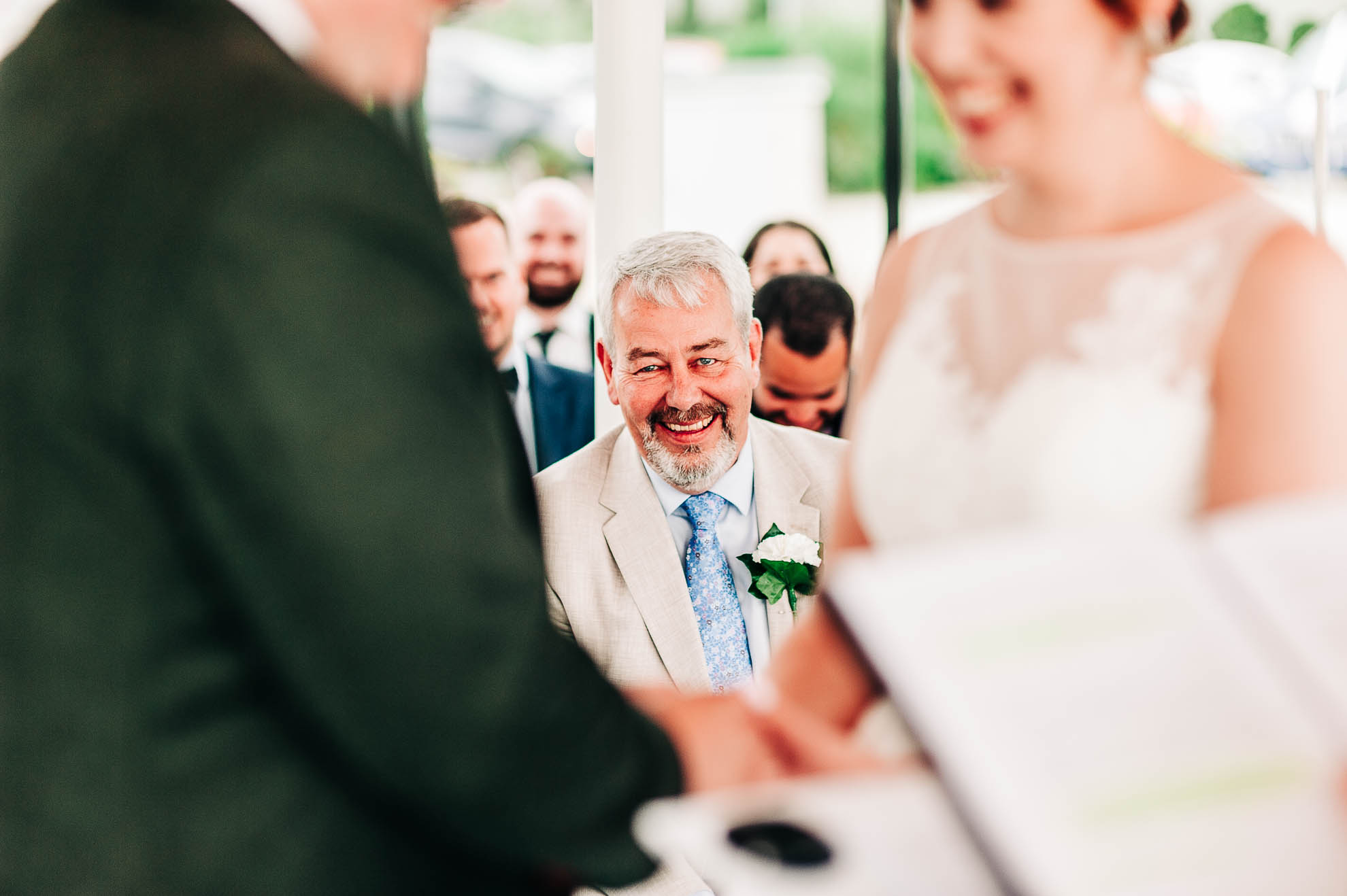Father of the bride looking very happy as the happy couple exchange wedding rings