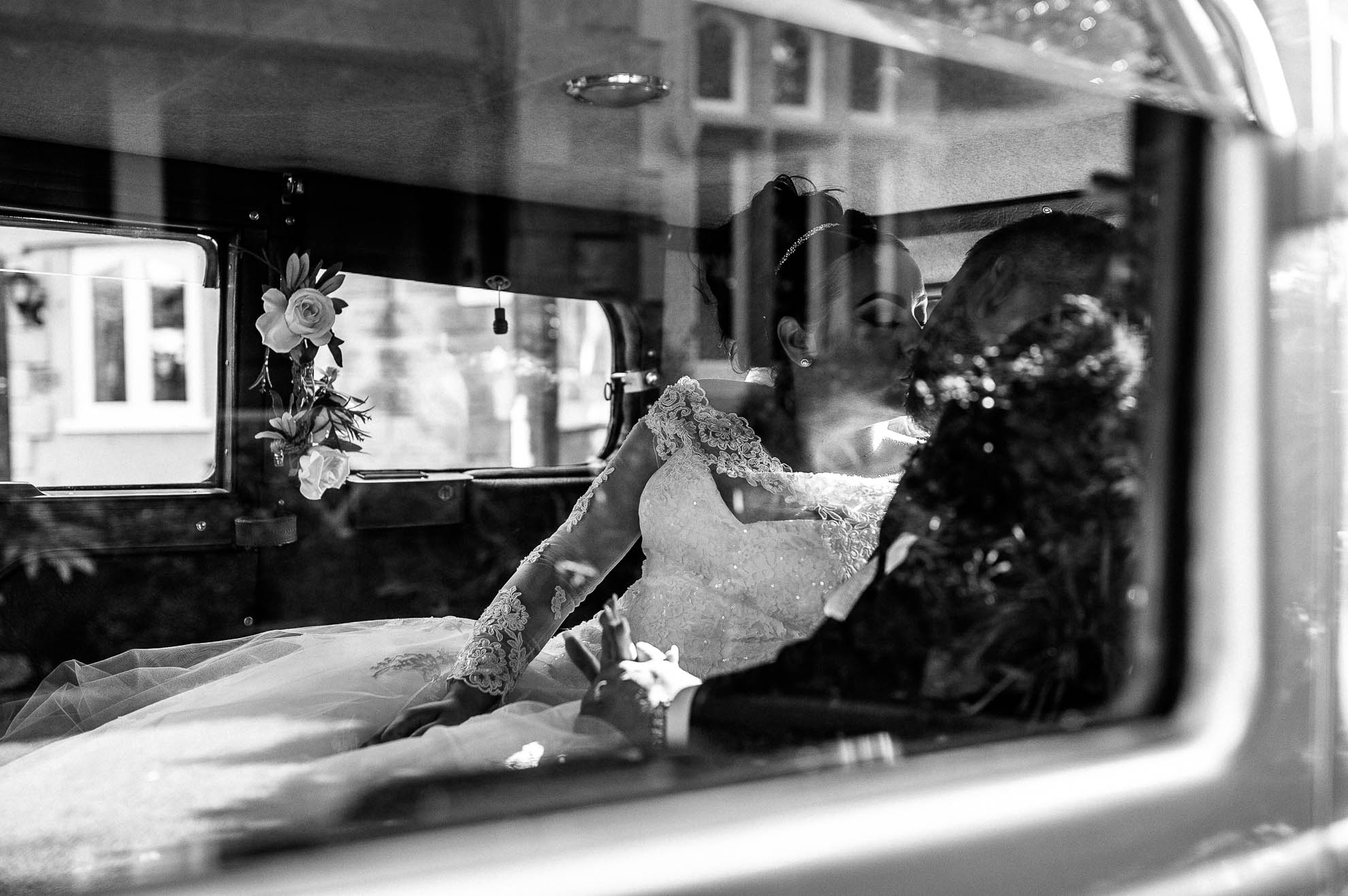 bride and groom kiss in wedding car