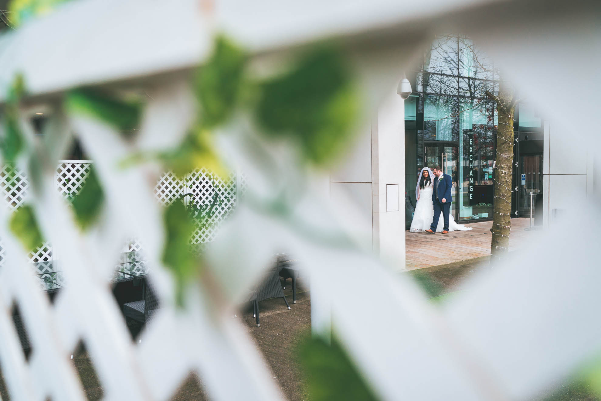 bride and groom shot through fence
