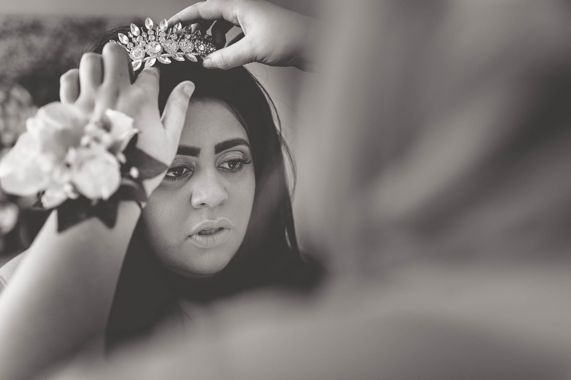 bridesmaid fits tiara on bride