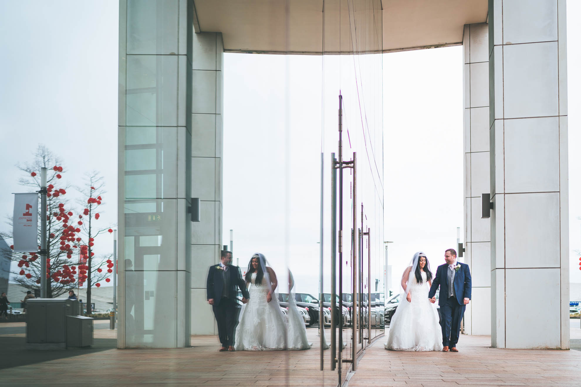 bride and groom walk reflection in mirror of Hilton liverpool
