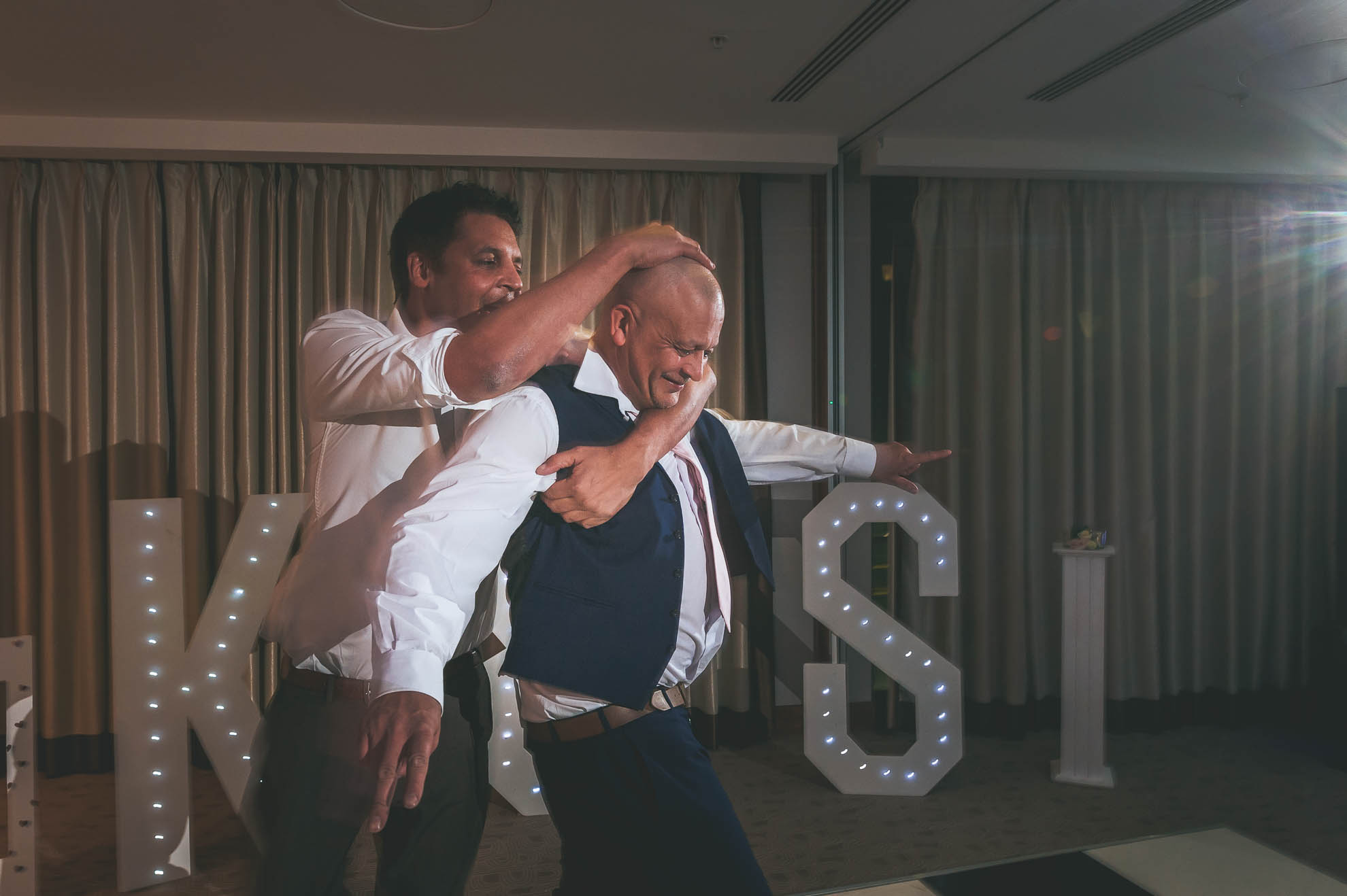 man wrestles playfully with father of the bride