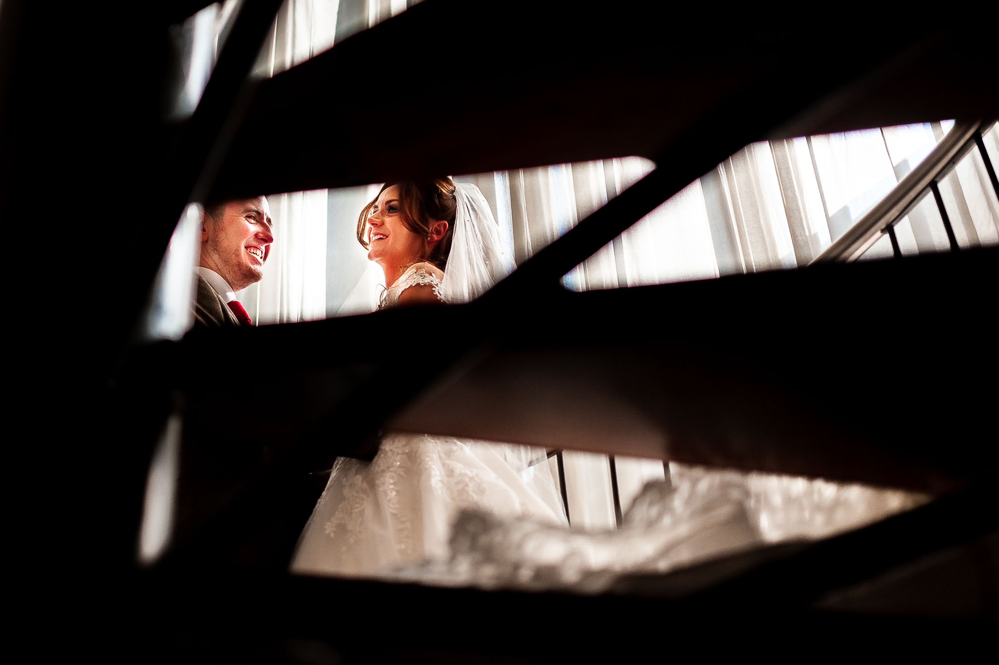 Bride and groom share a joke on spiral staircase