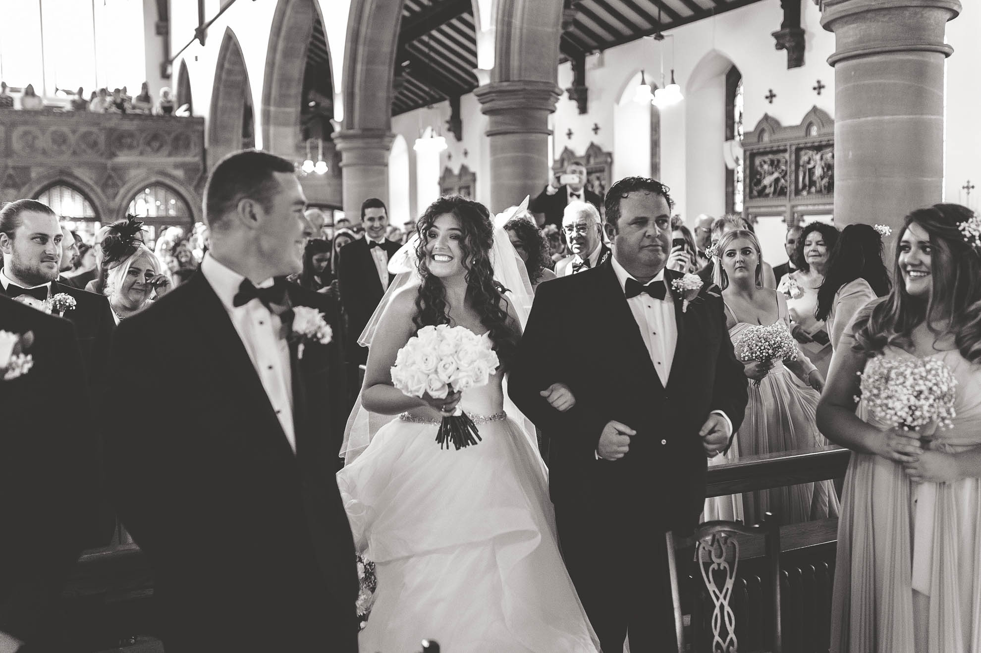 Bride and groom smile at each other as bride arrives at altar