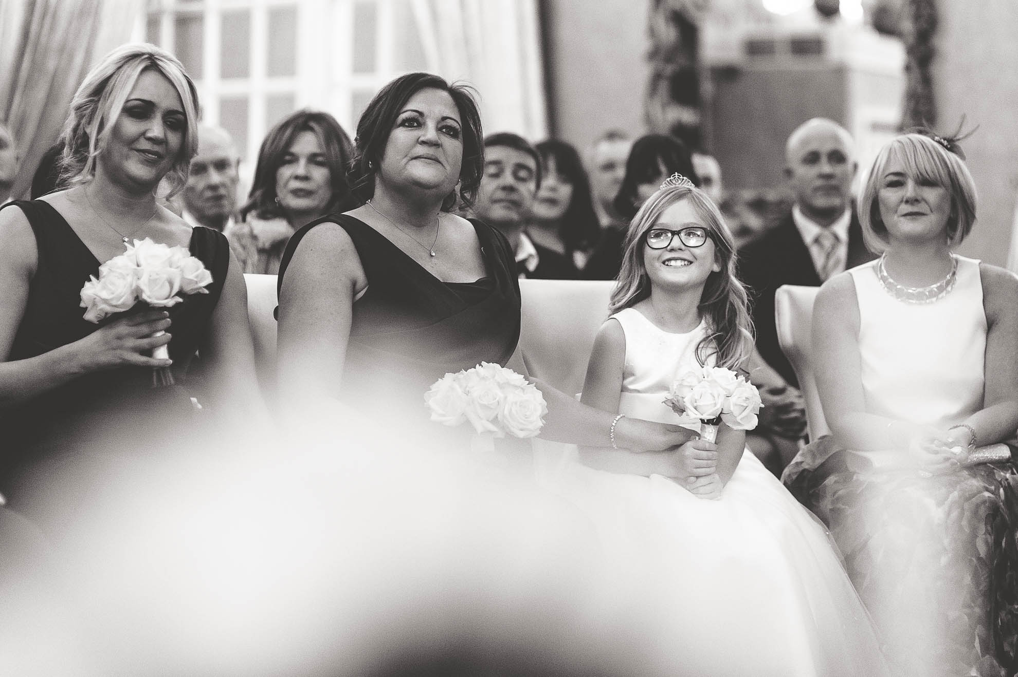 Bridesmaids and flower girl smiling during the exchange of rings