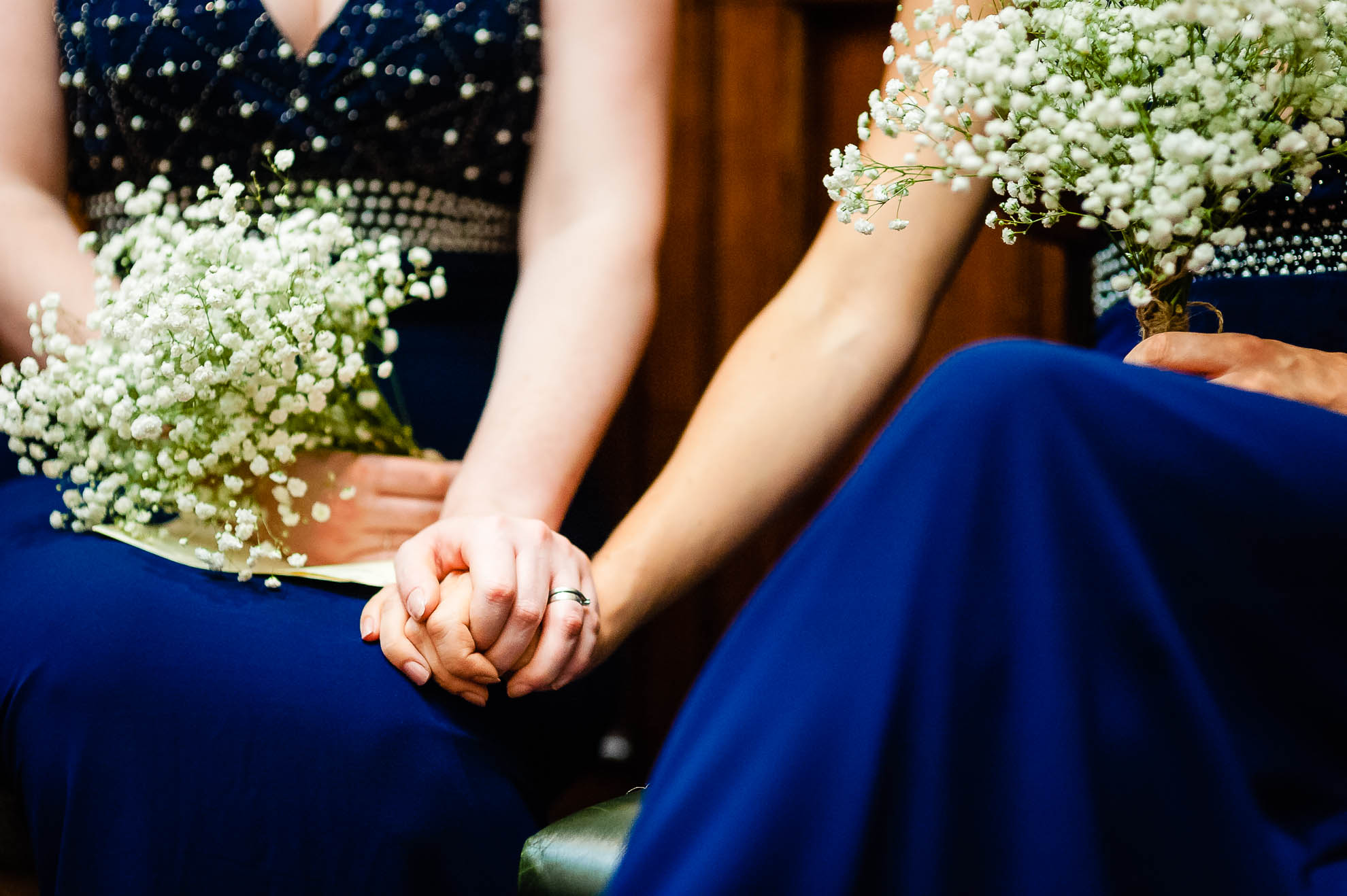 Bridesmaids hold hands during the exchange of vows