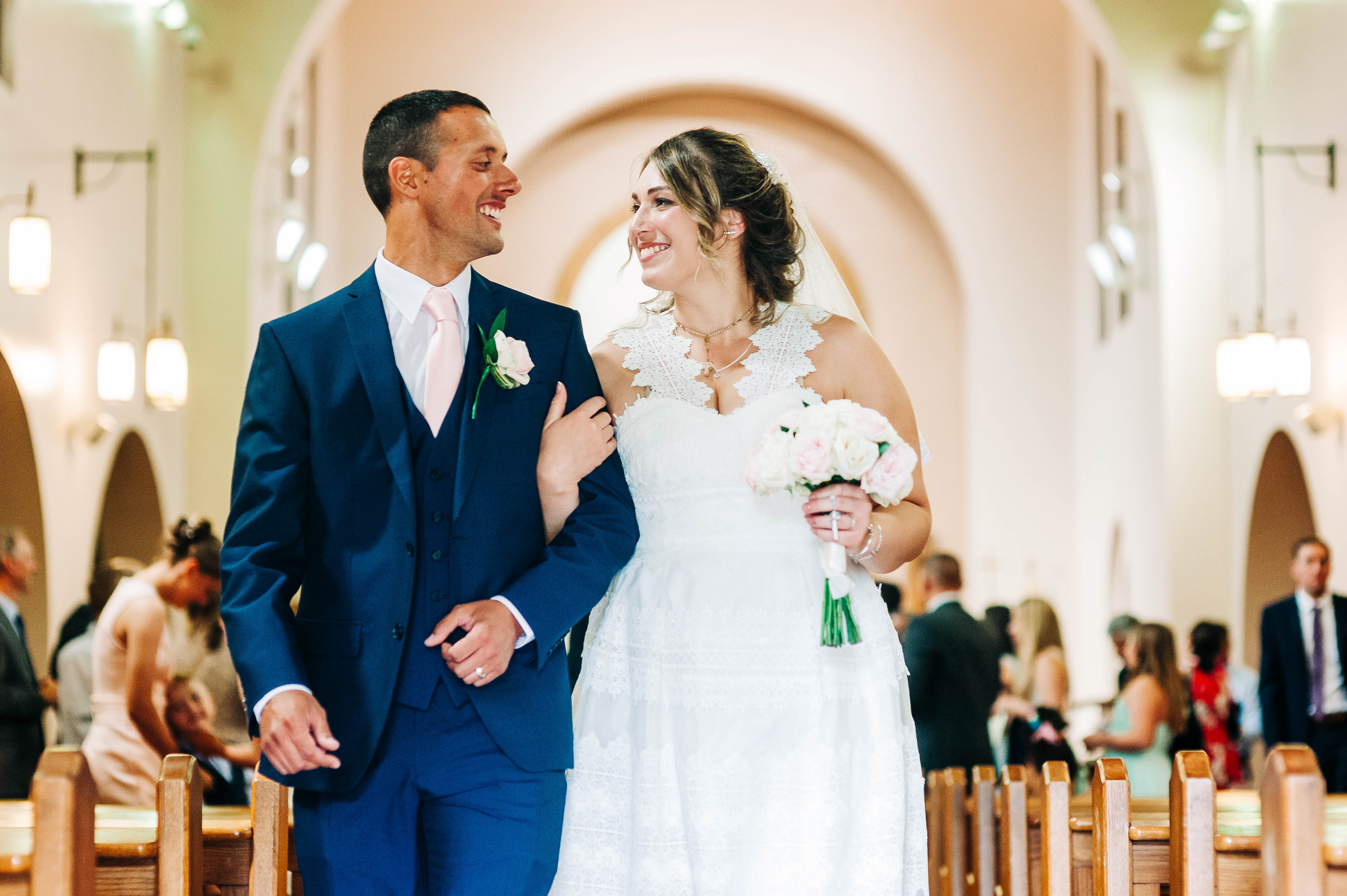 bride and groom smile at each other as they walk back down the aisle