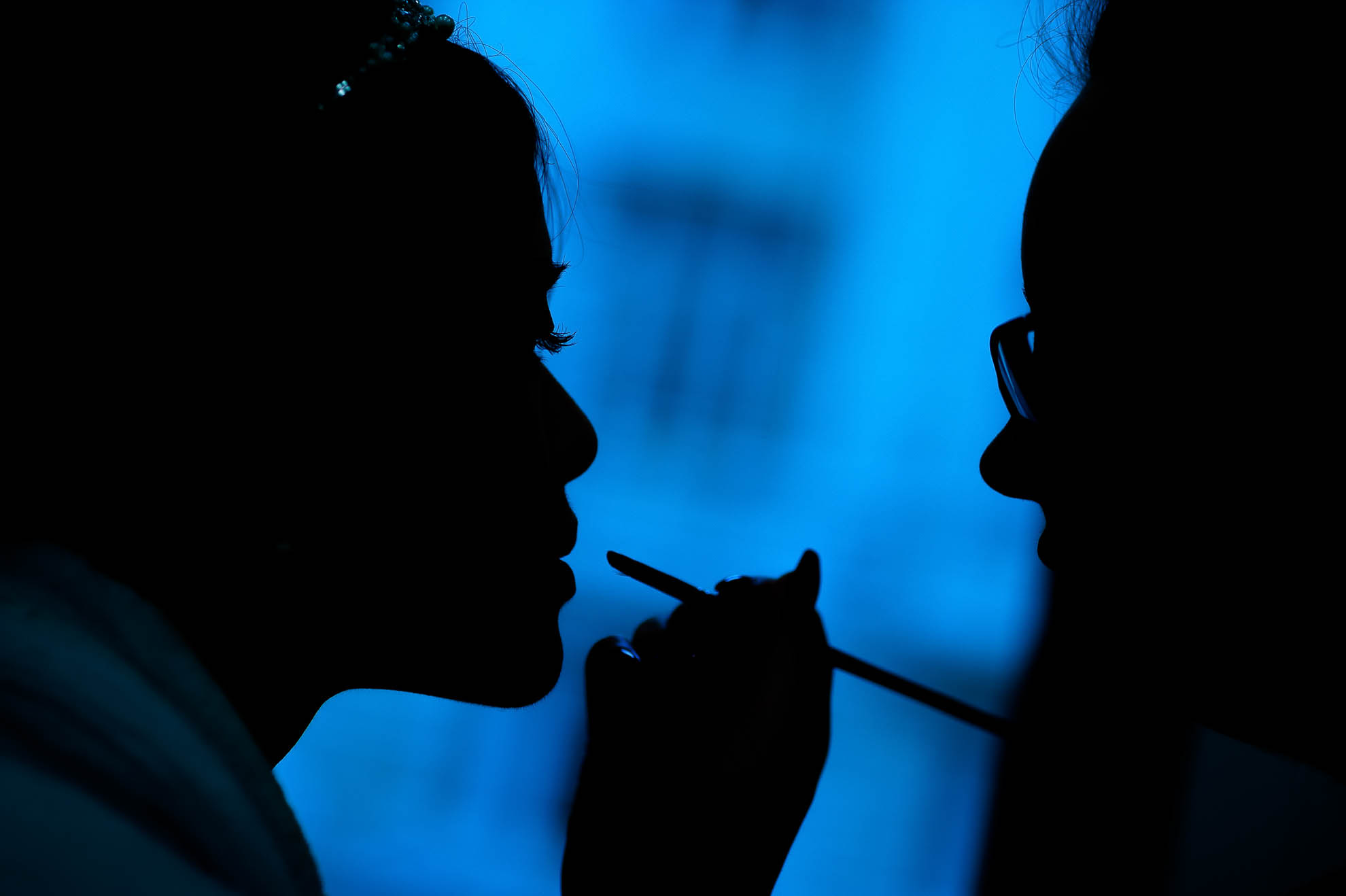 Silhouette of bride having make up applied