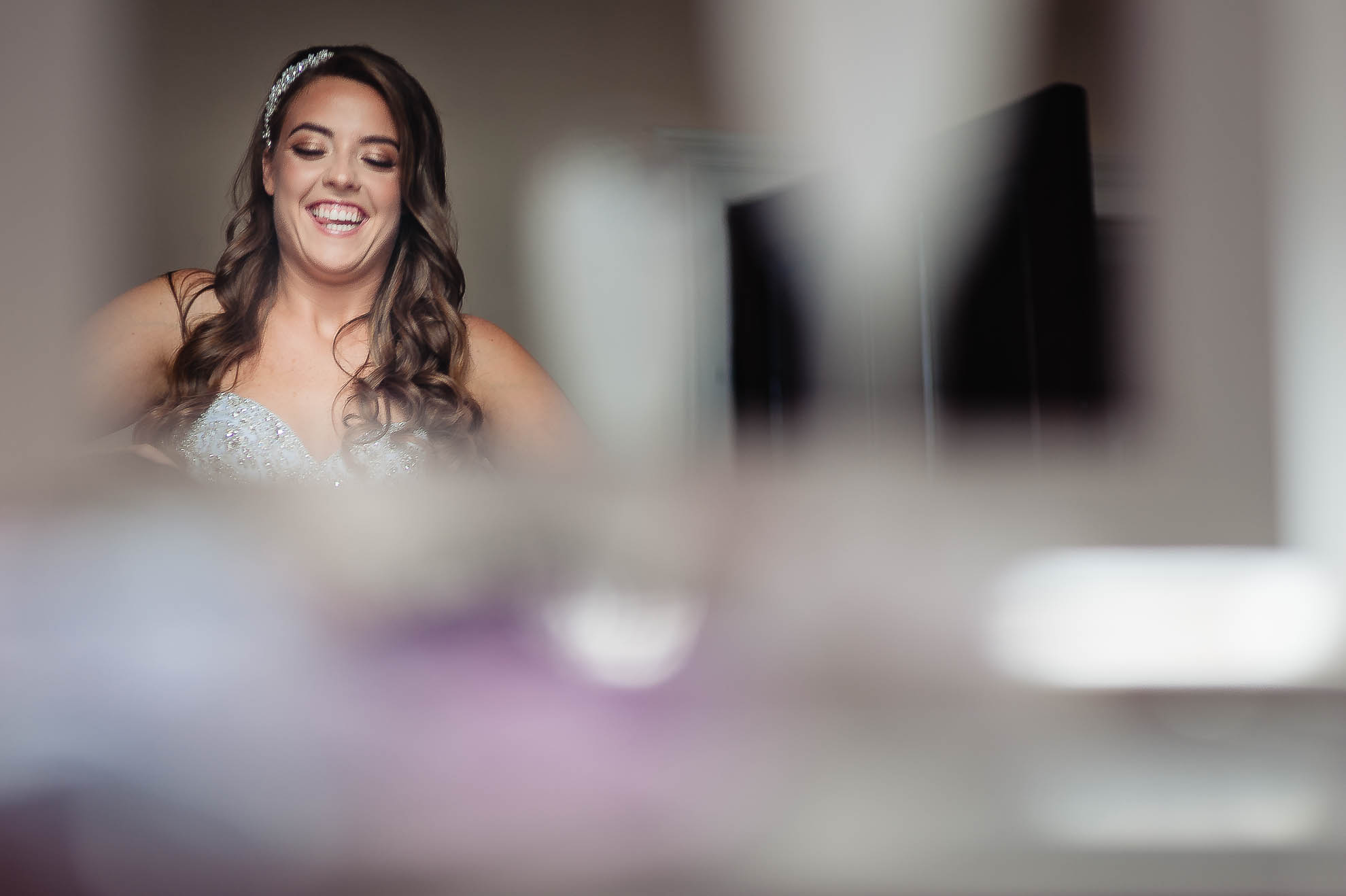 Bride laughing as bridesmaids adjust her dress