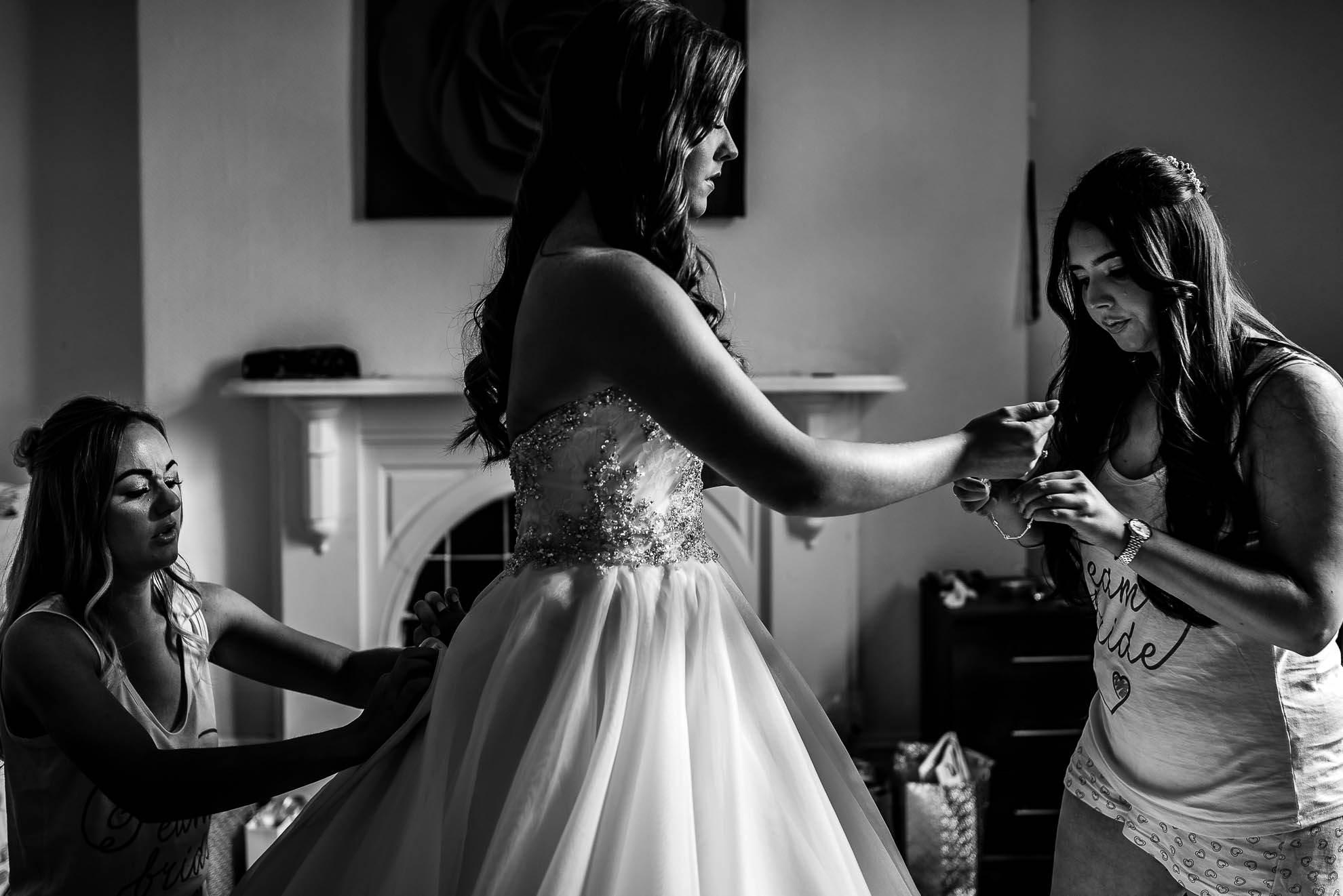 Bridesmaids help the bride into her dress