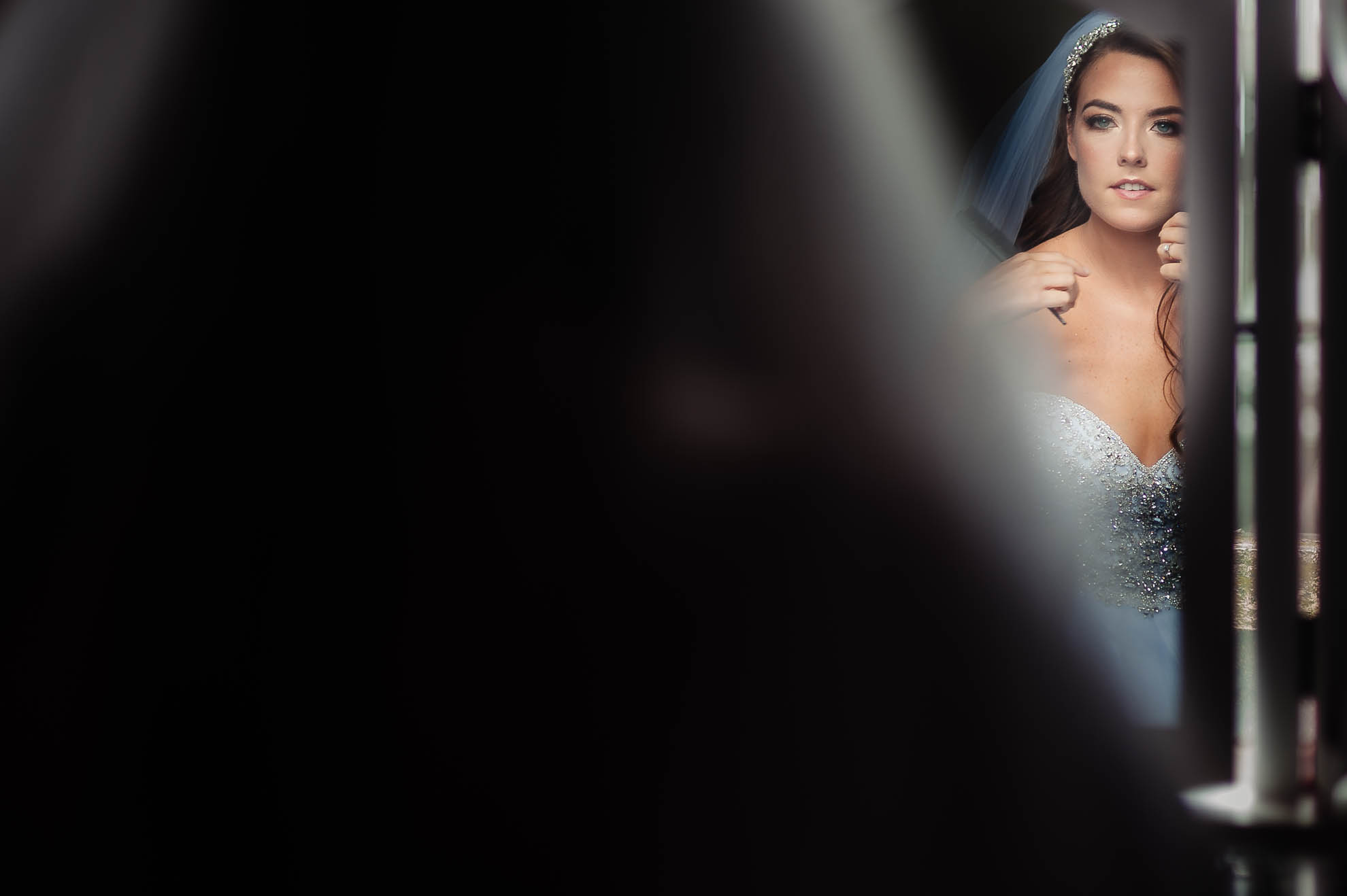 Bride looks into mirror after putting her dress on