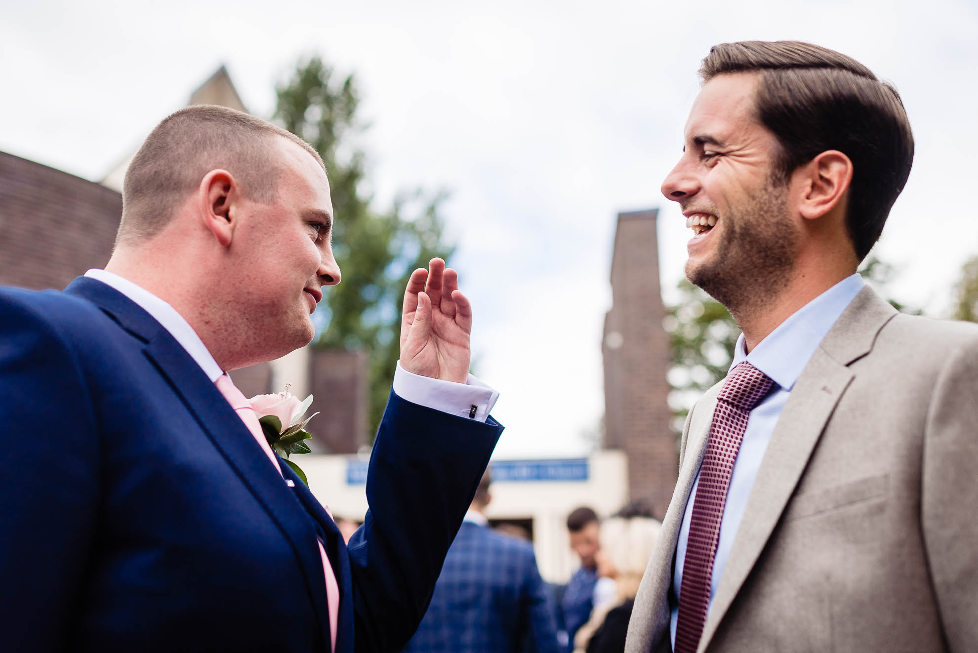 Groom shares a joke with a guest at the church