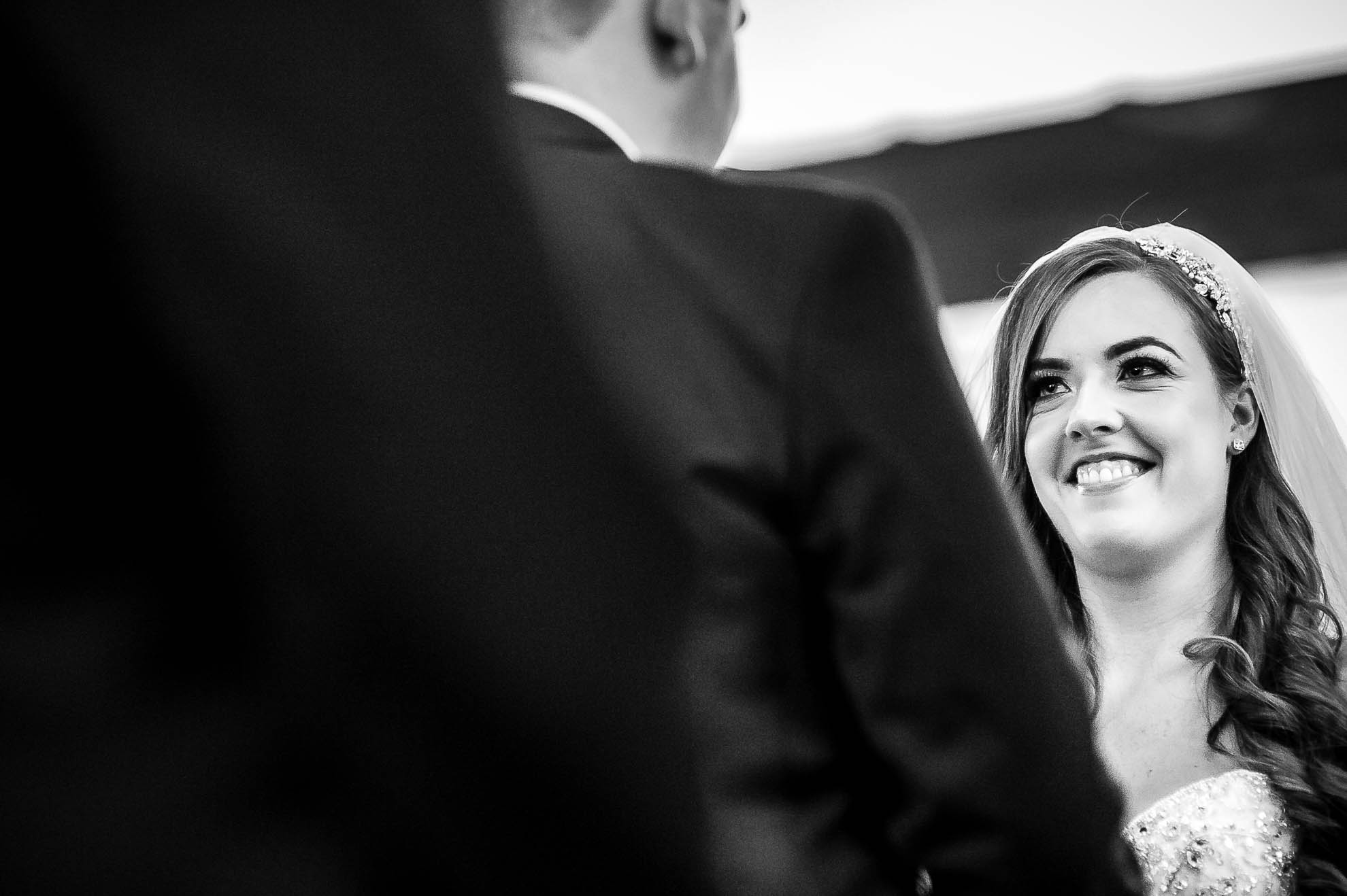 Bride smiles at the groom during the exchange of rings