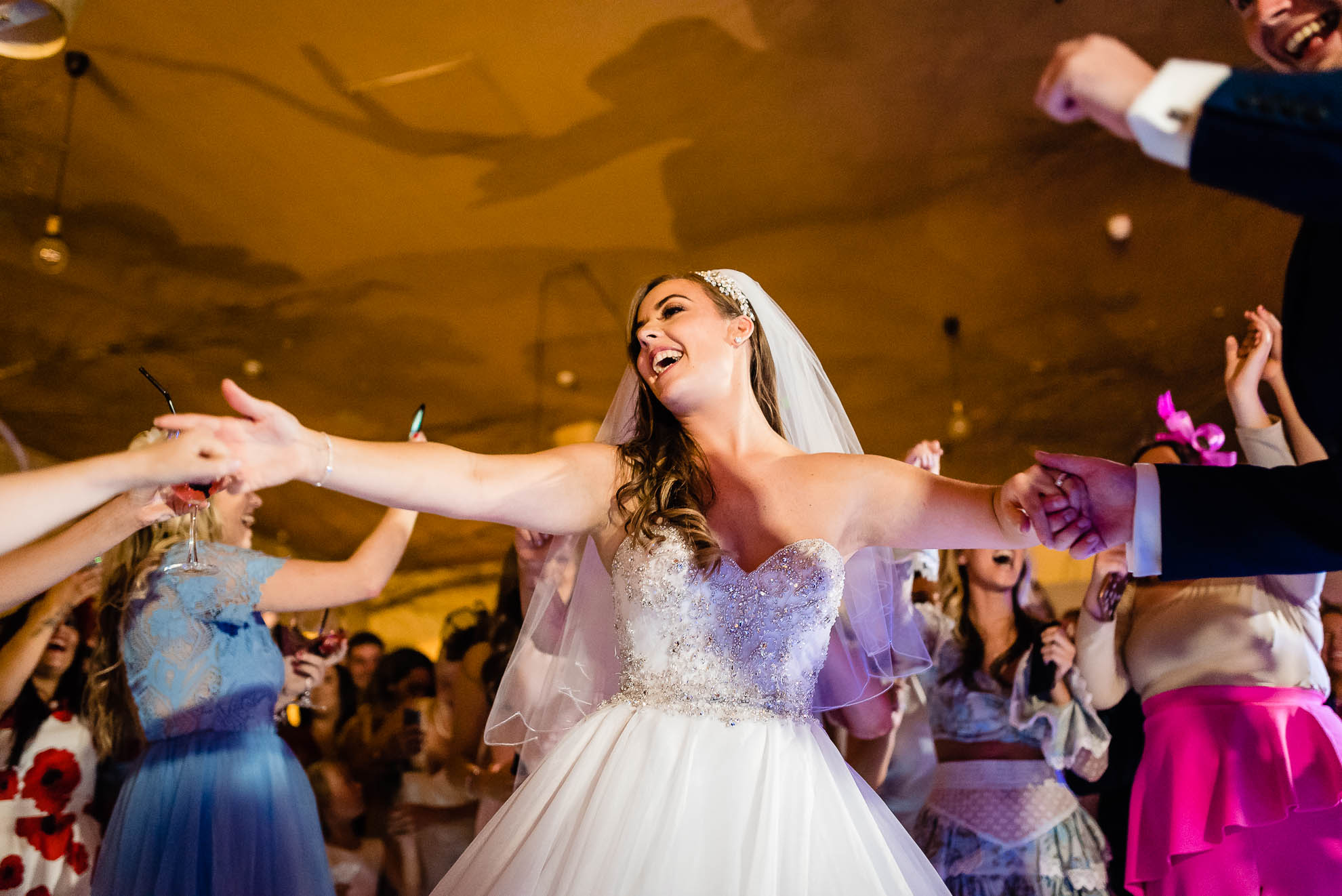 Bride and groom hold hands with guests while dancing