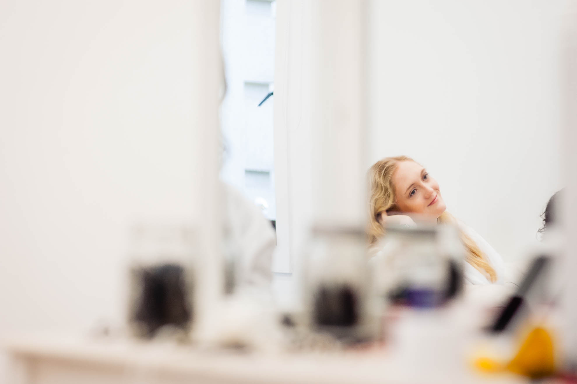 Bridesmaid reflection in mirror during bridal preparations