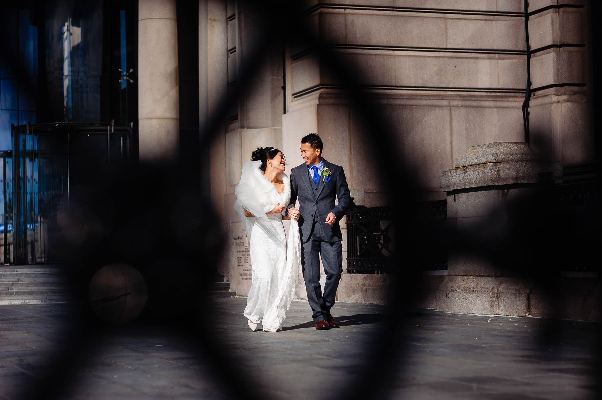 Bride and groom walking past Liver building