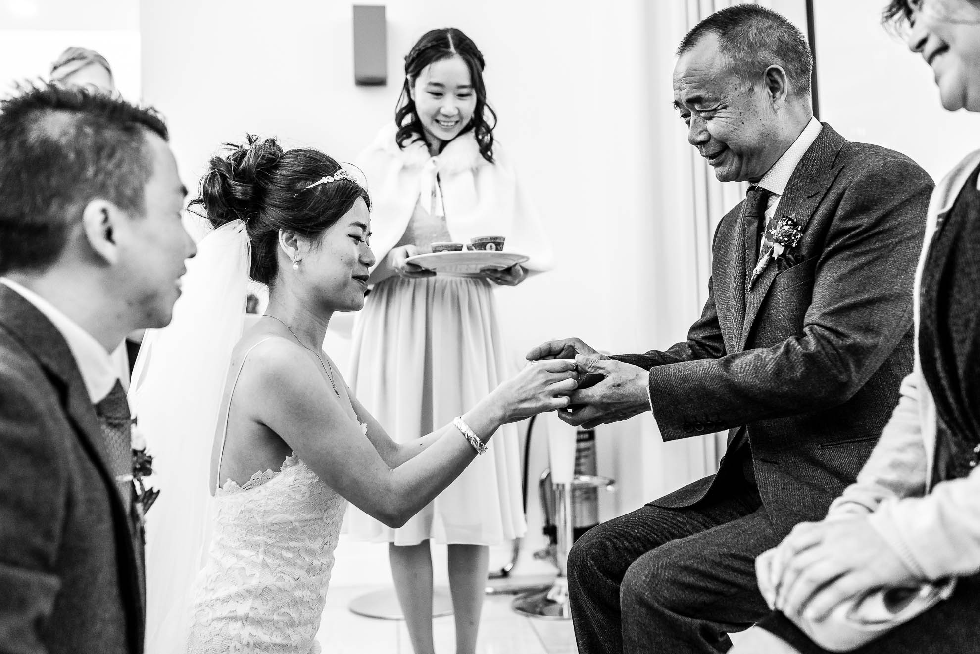 Bride gives her father tea during tea ceremony