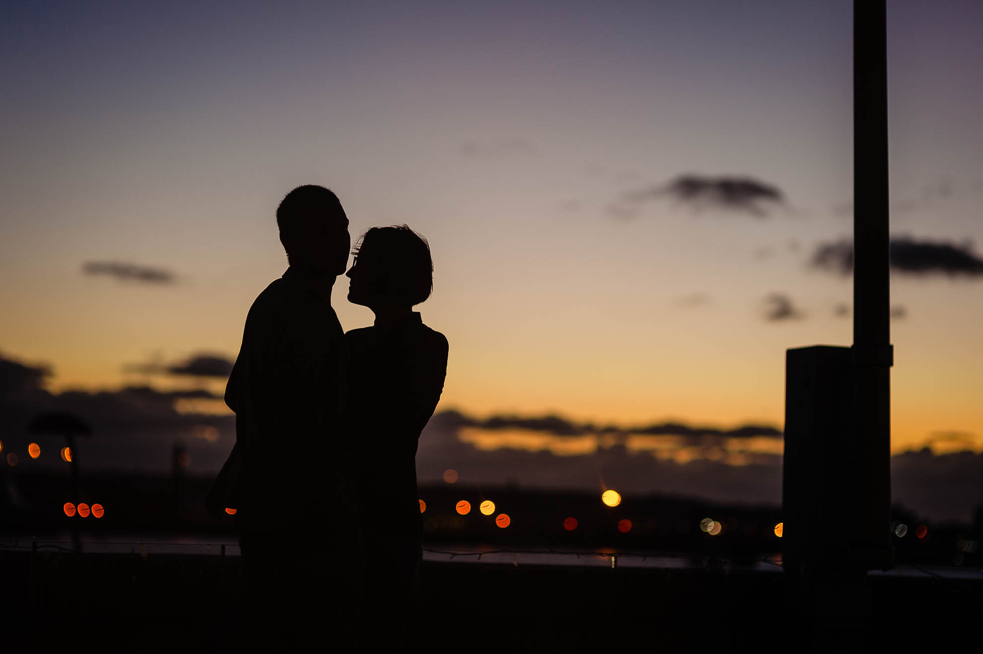 Silhouette of couple behind sunset sky