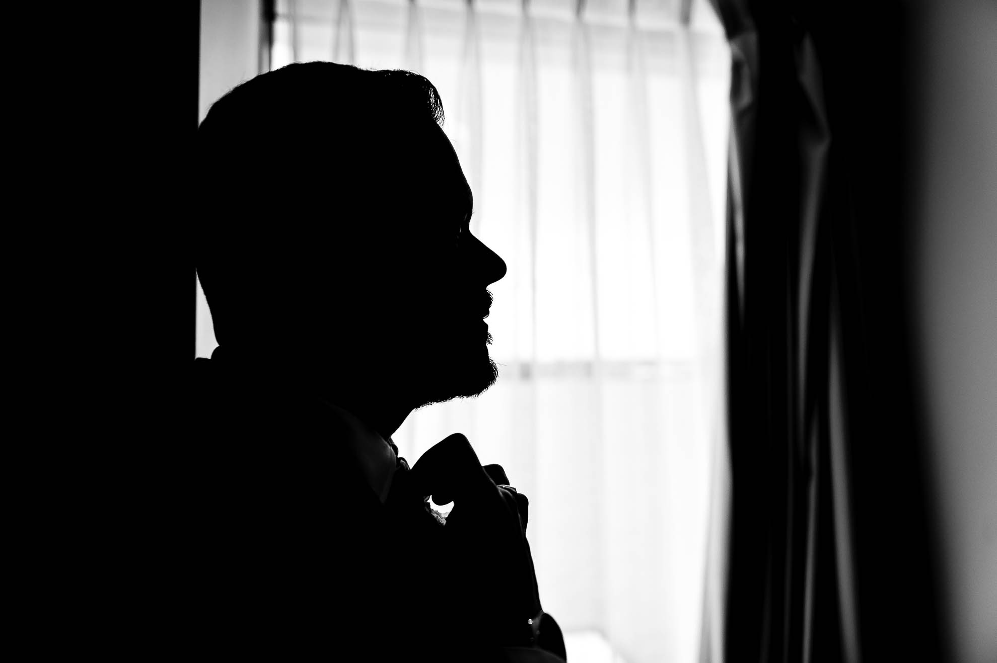 Groom silhouette as he adjusts his tie