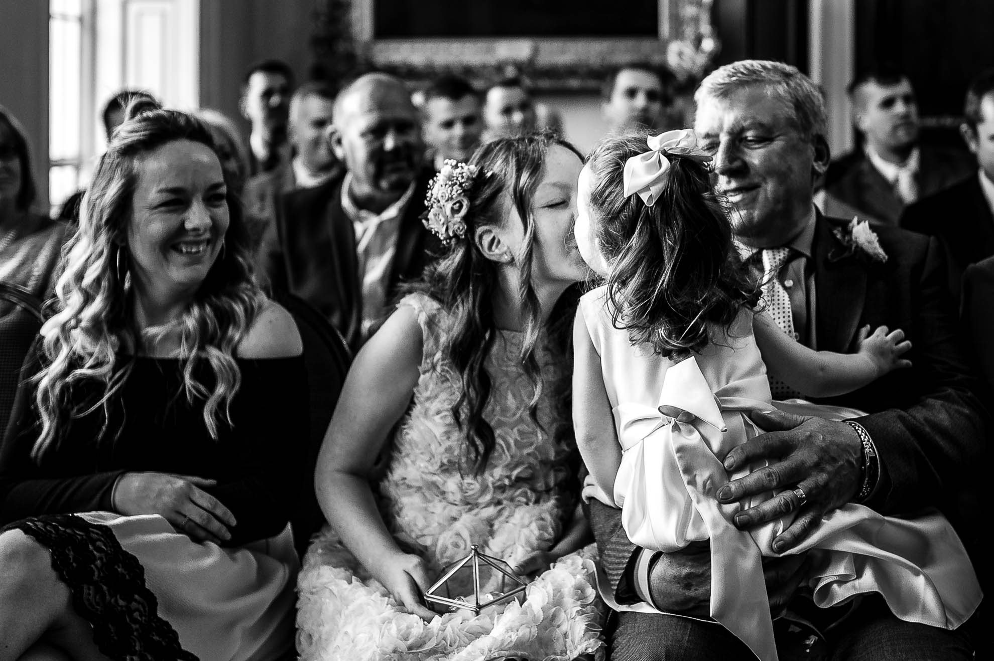 Flower girl gives big sister a kiss during the exchange of rings