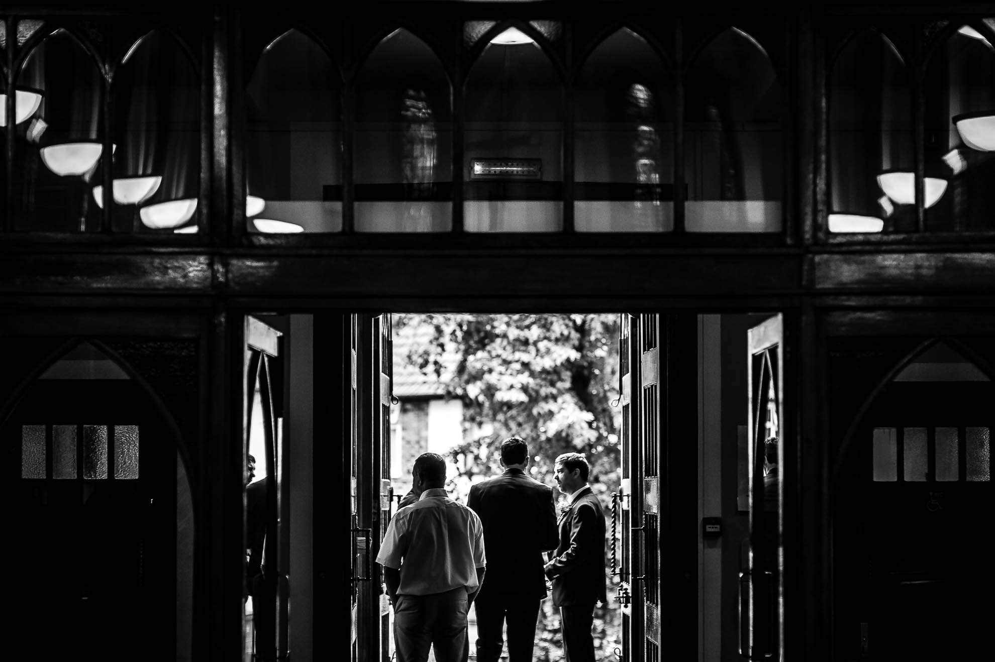 Groom talks to best man at entrance to church