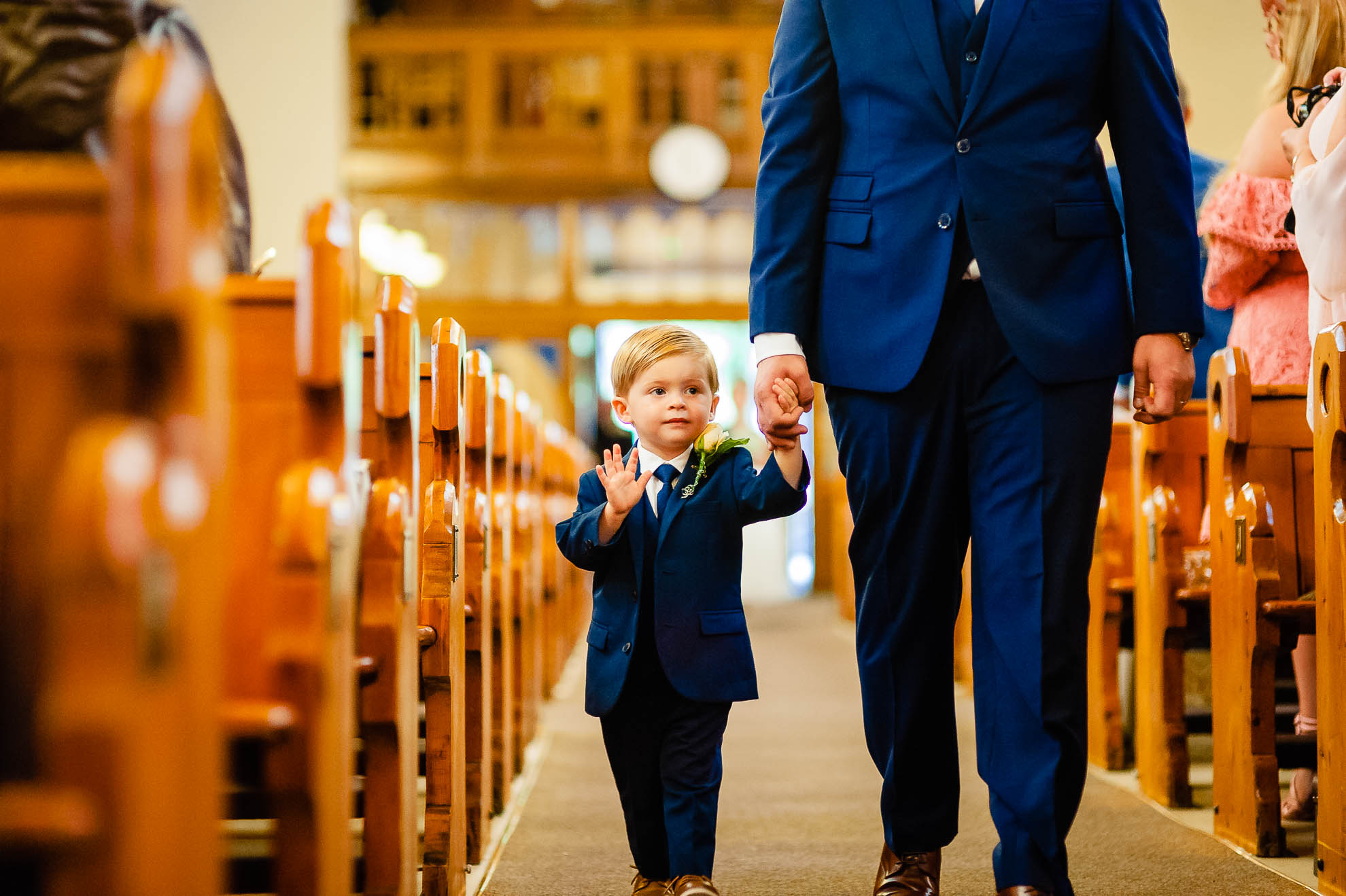 Page boy waves as he walks up ailse