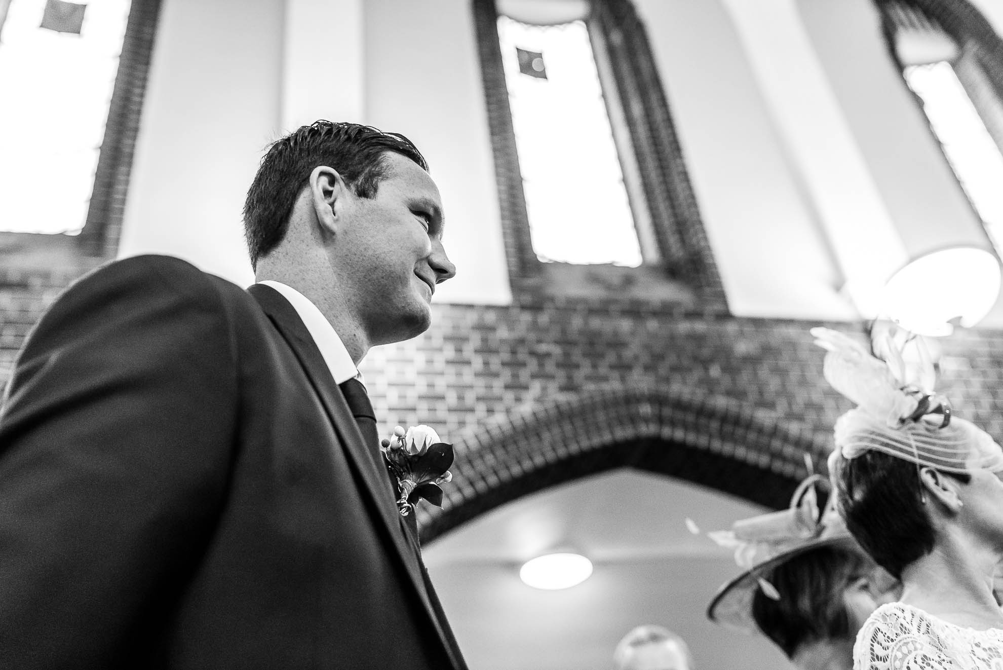 Groom smiles as he watches his bride walk up the ailse
