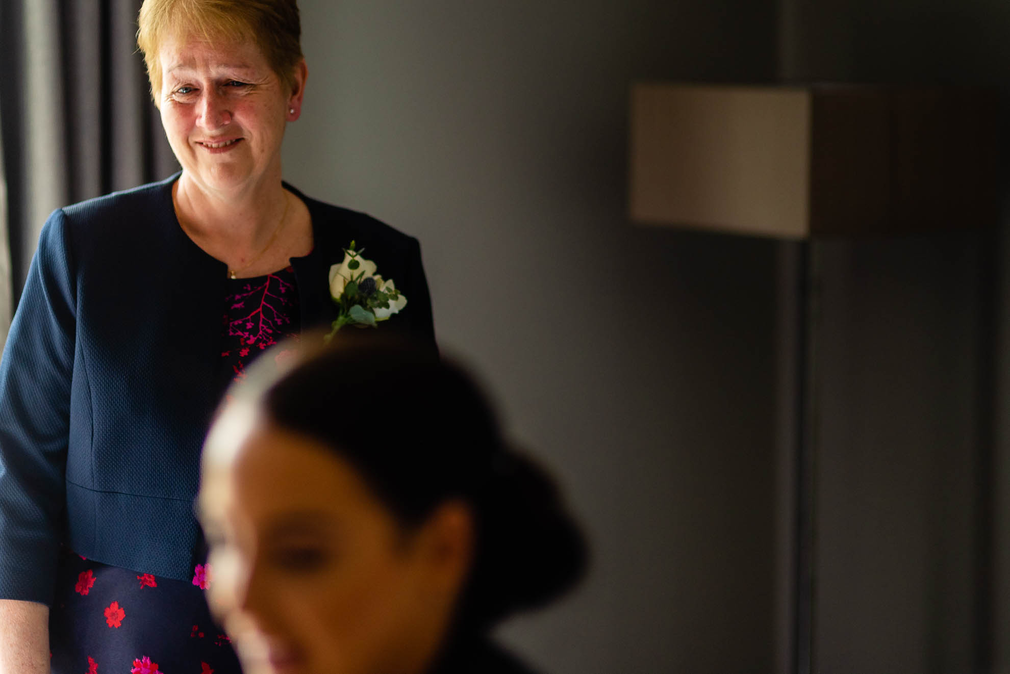 Mother of the bride smiles as she looks at the bride