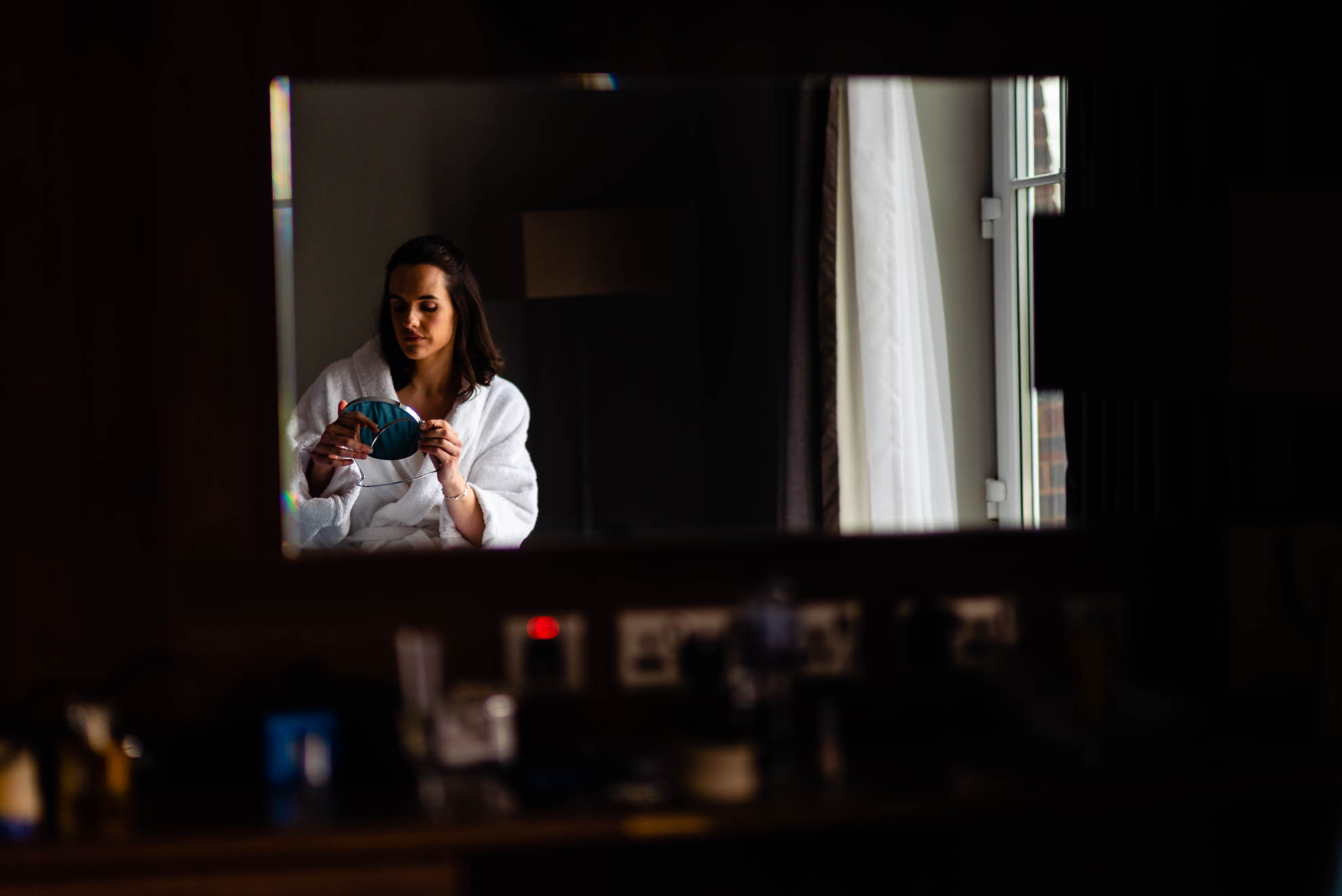 Bride applying make up in the mirror