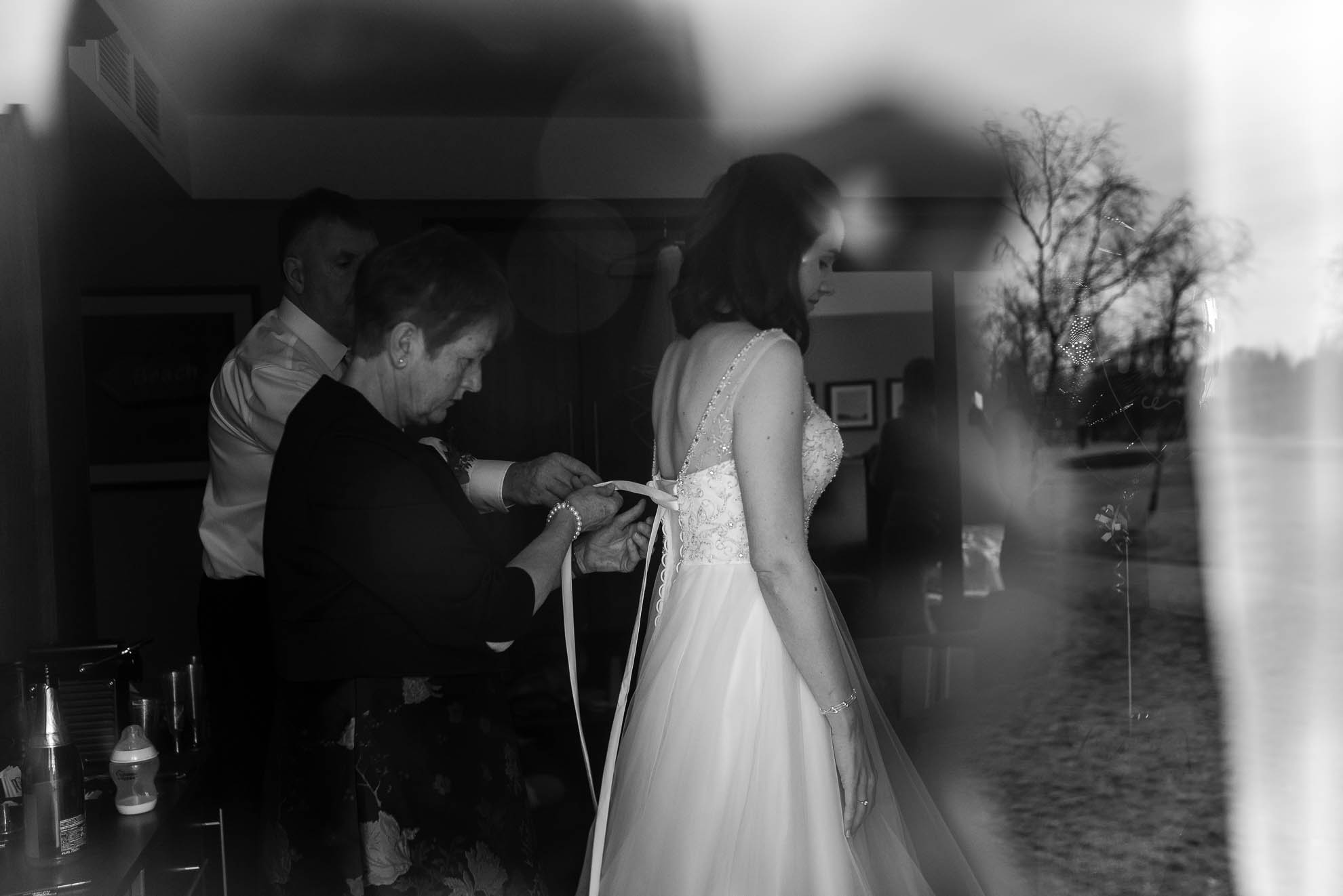 mother of the bride helping the bride into her wedding dress