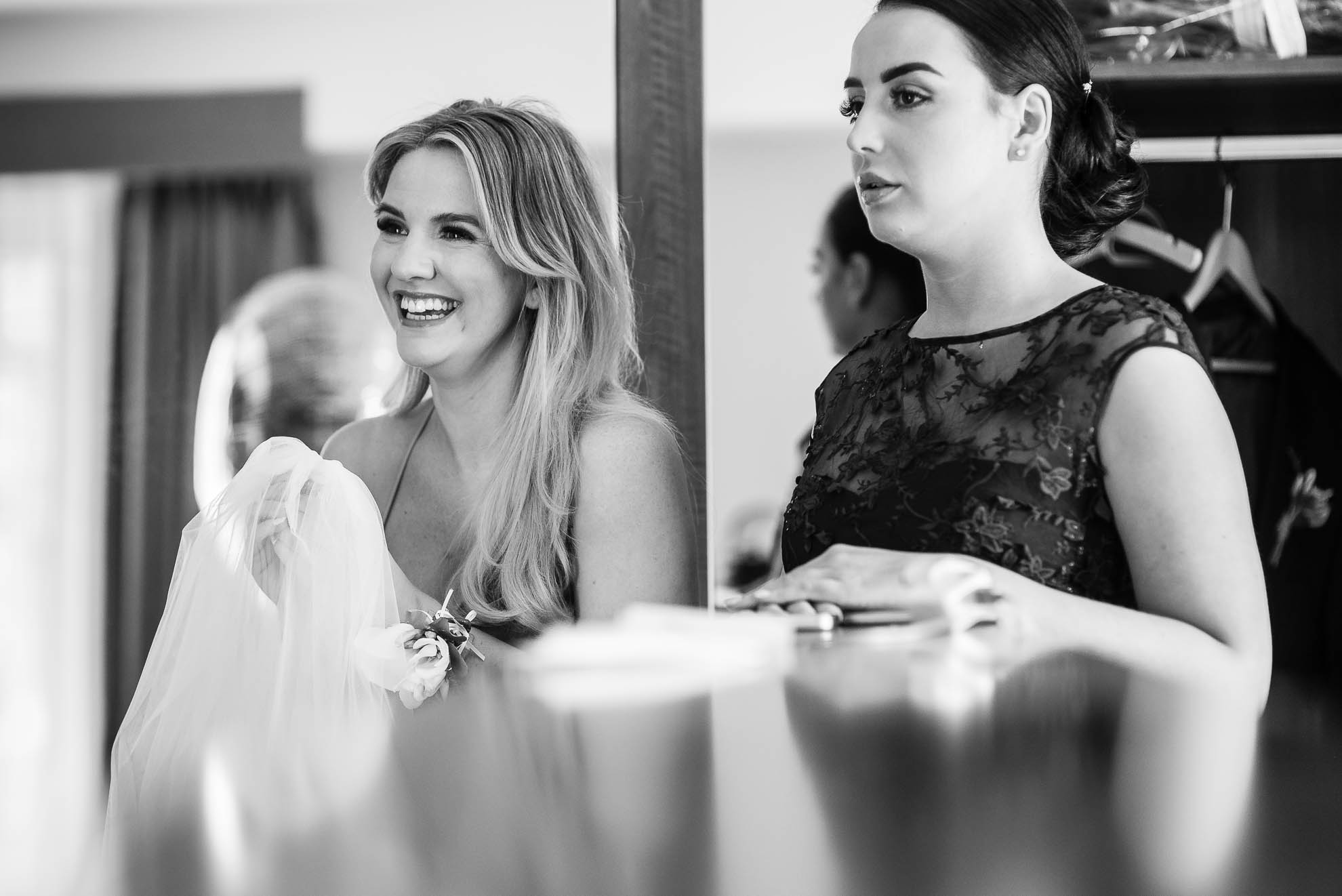 Bridesmaids smile as they look at the bride in her dress