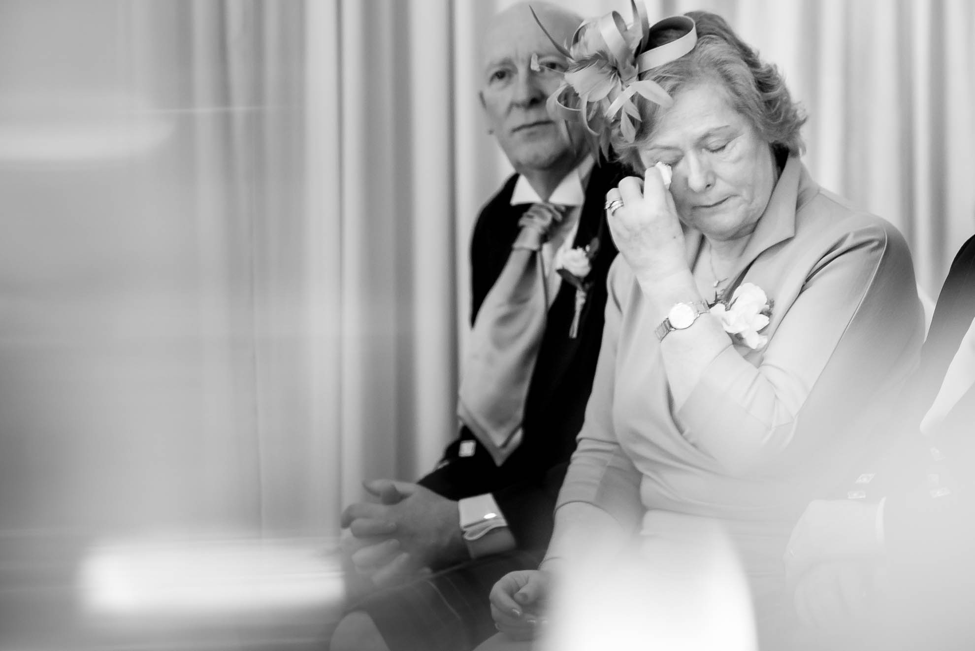 Mother of the groom wipes away a tear during the exchange of the rings